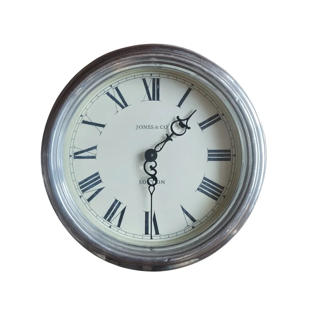 Round wall clock with silver frame, Roman numerals, black hour and minute hands, and a white face. The time shows approximately 1:04.