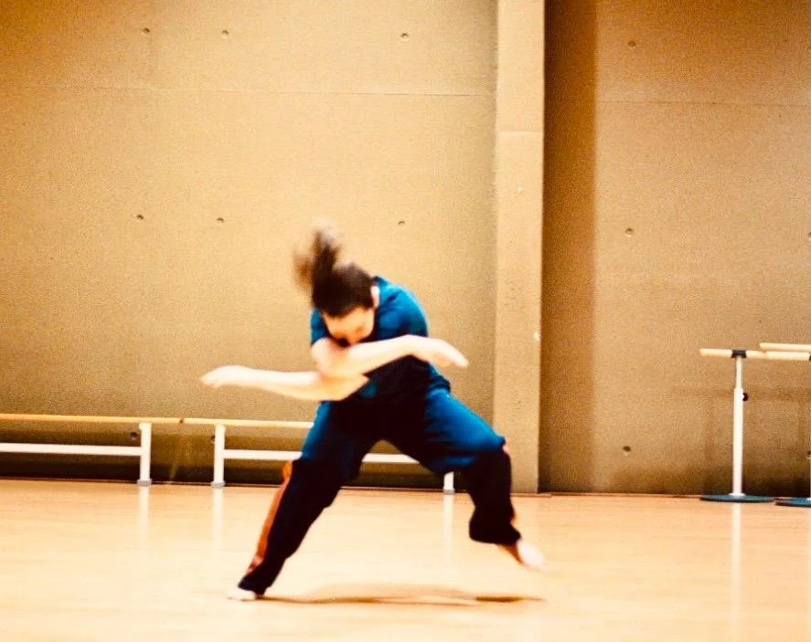 Sessie danstherapie: Persoon in groene sportkleding die een dansbeweging maakt in een dansstudio.