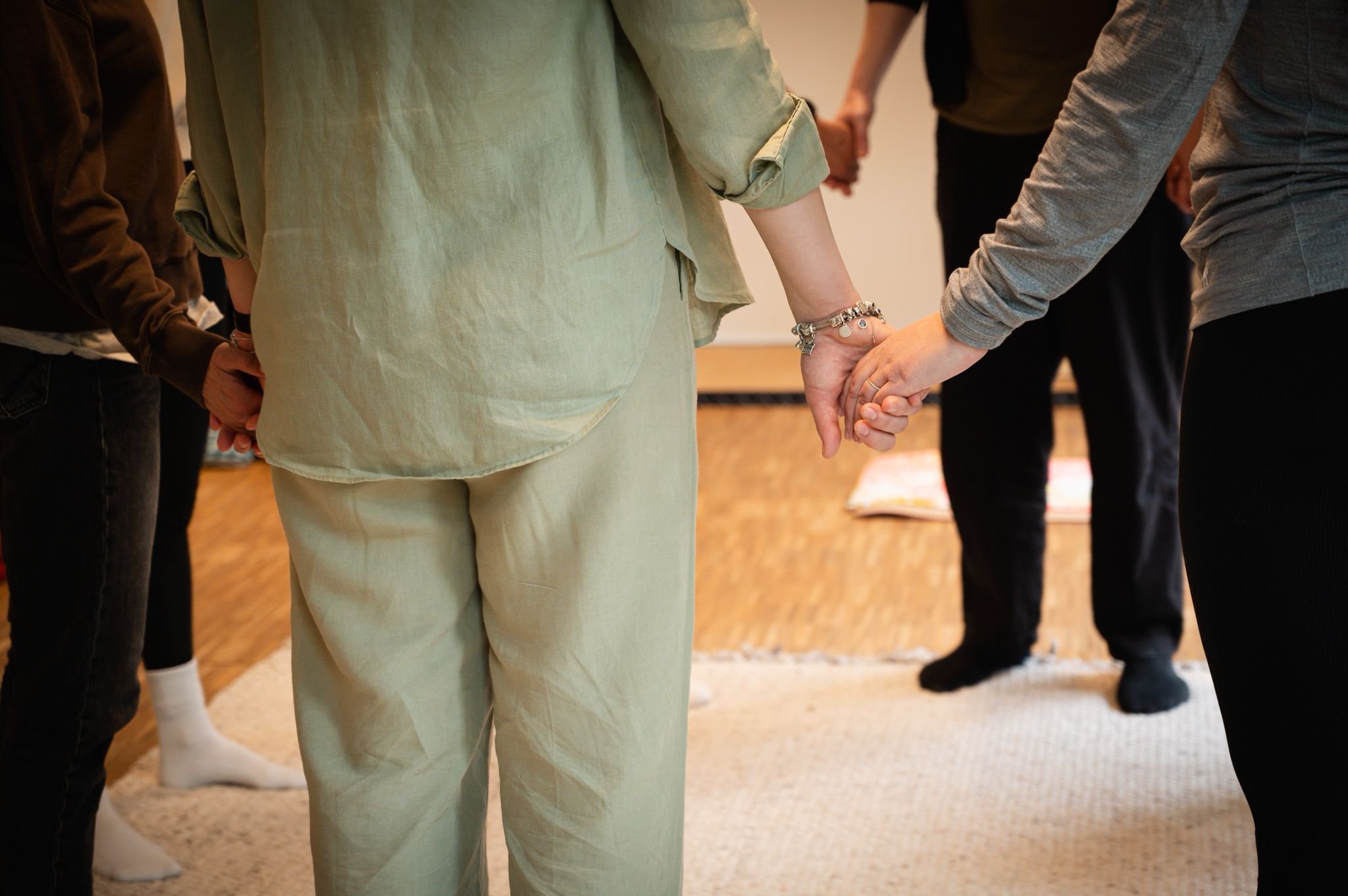 A group of people holding hands in a circle during a gathering or support session.