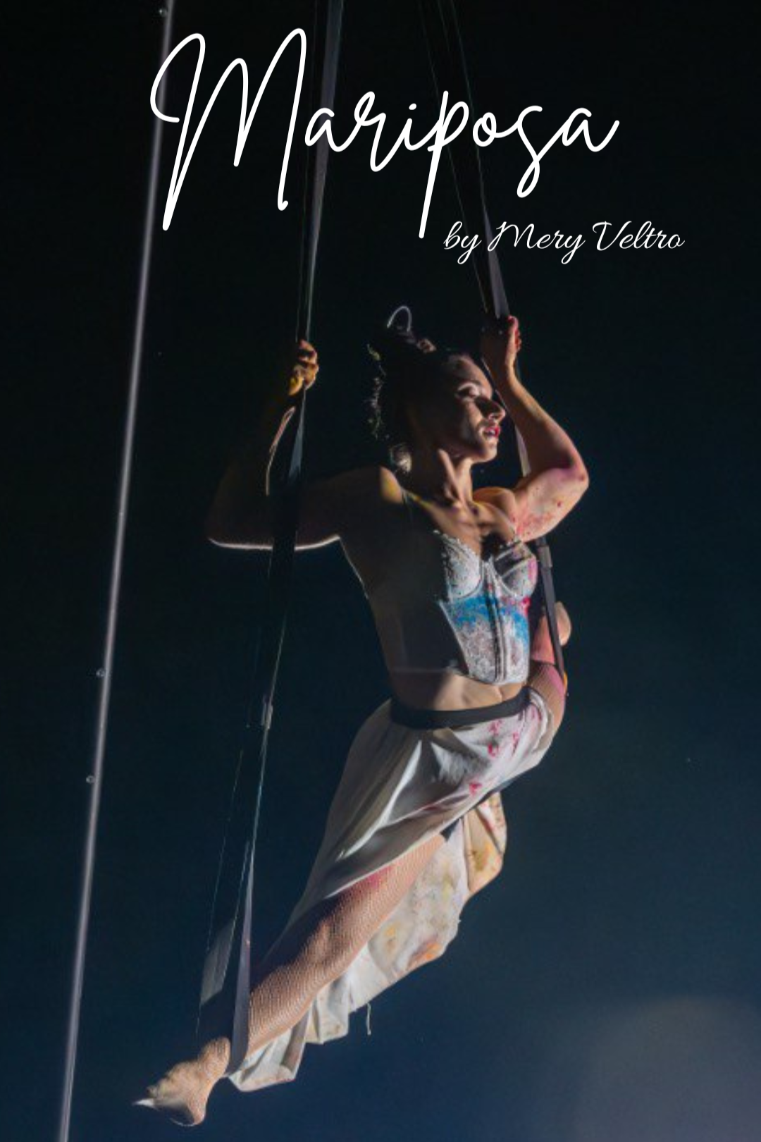 A woman performing an aerial silk act during a circus show at night, with dark background and stage lighting, wearing a colorful costume and heels.