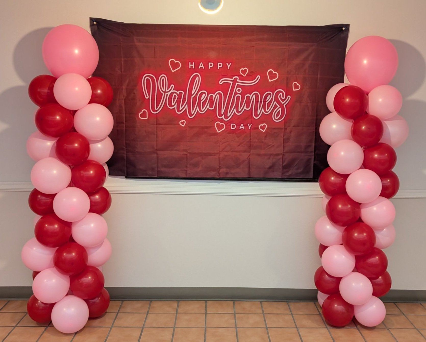 red and pink balloon columns with a happy valentines day banner