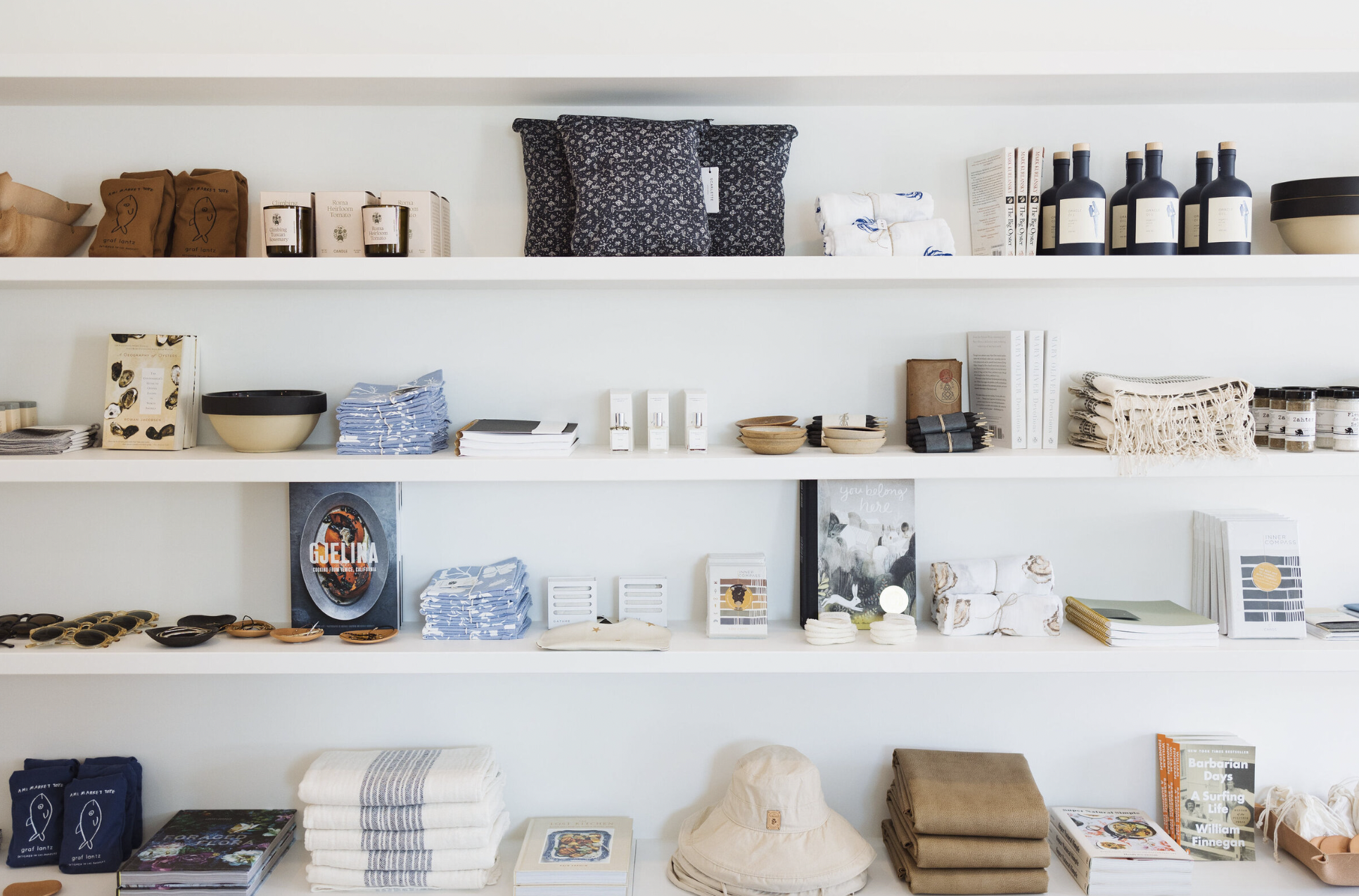 White shelves filled with various home decor, books, and organized goods including candles, dishes, clothing, and accessories.