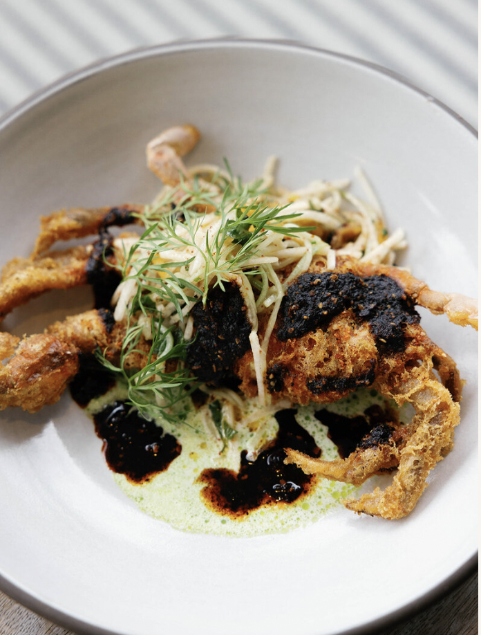 Fried squid with herbs and dark sauce on a white plate