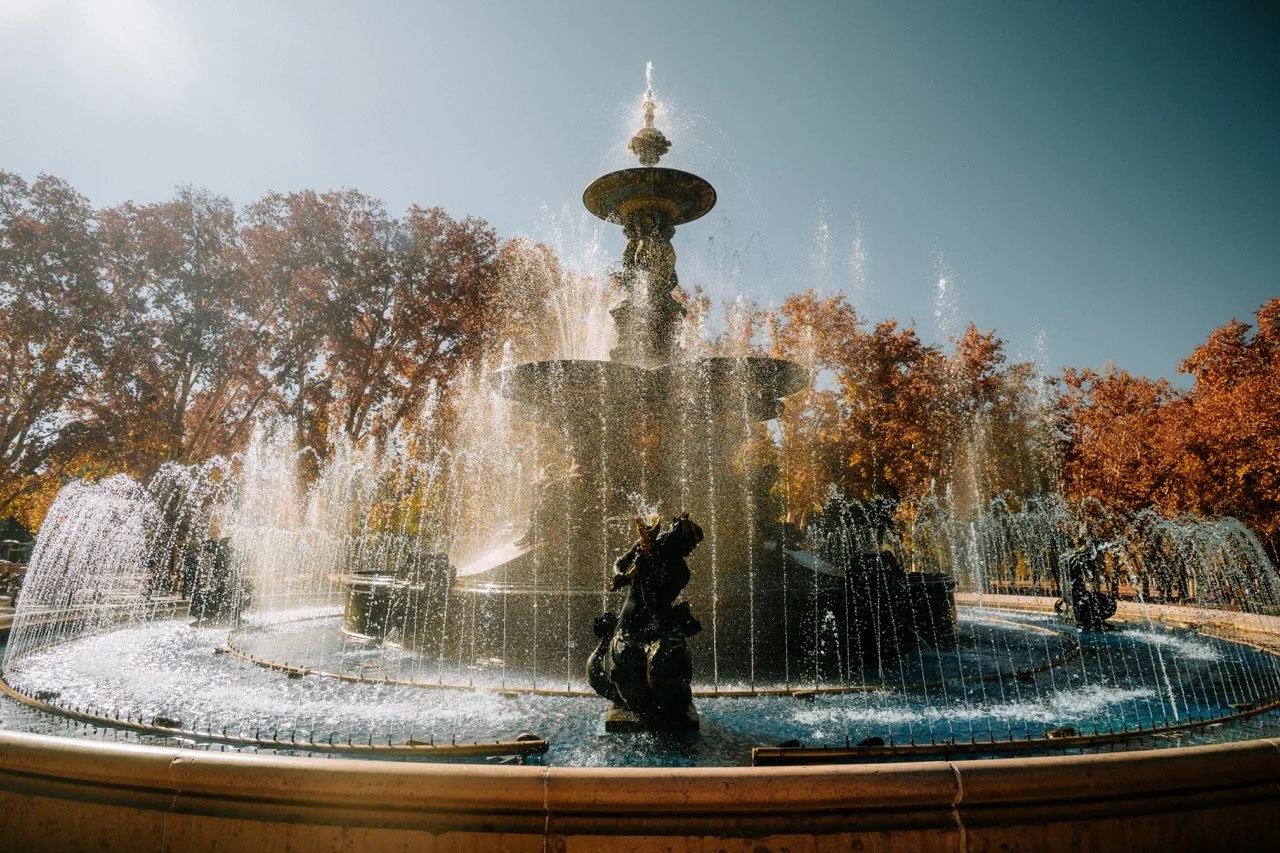 Fuente de agua en un parque con árboles de hojas otoñales