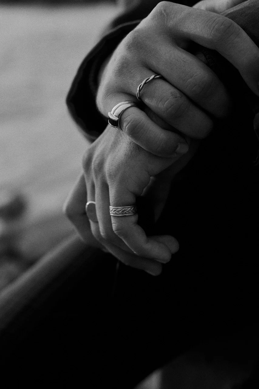 Manos entrelazadas con anillos, en blanco y negro.