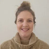 A smiling woman in a beige jumper