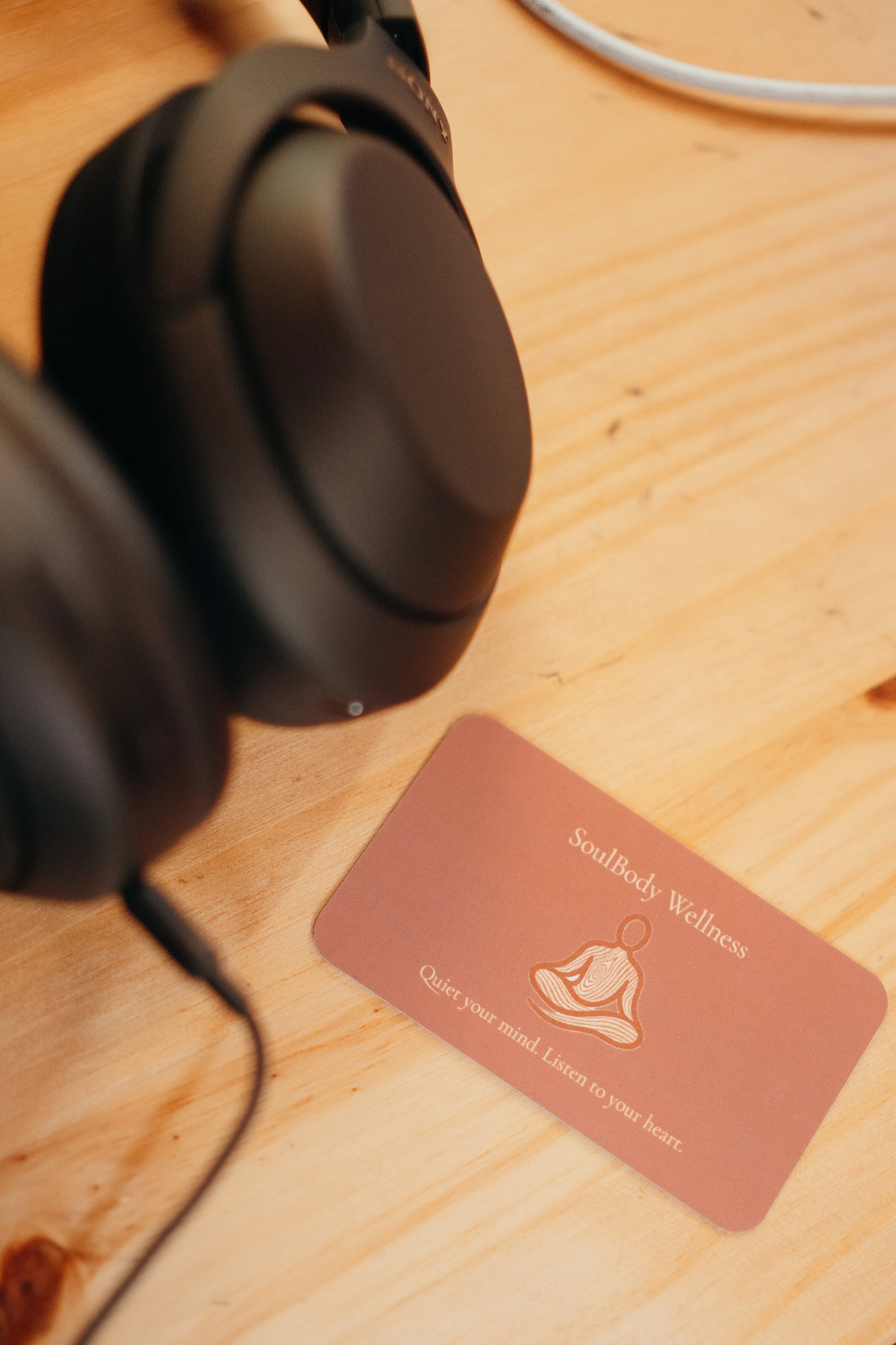 SoulBody Wellness card beside headphones on a wooden table