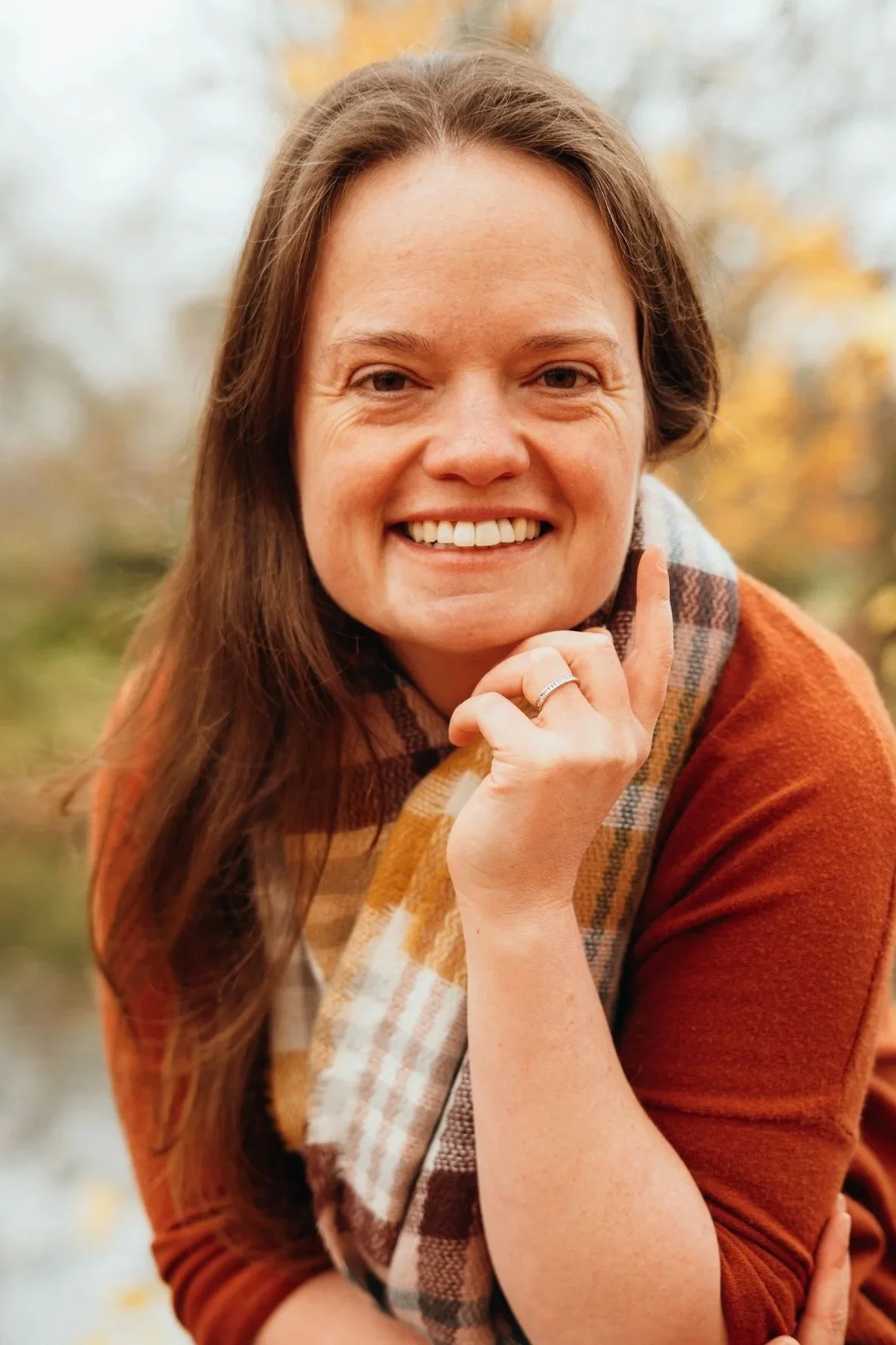 Woman sitting outside with a gentle smile on her face; ease, breathwork; self-regulation.
