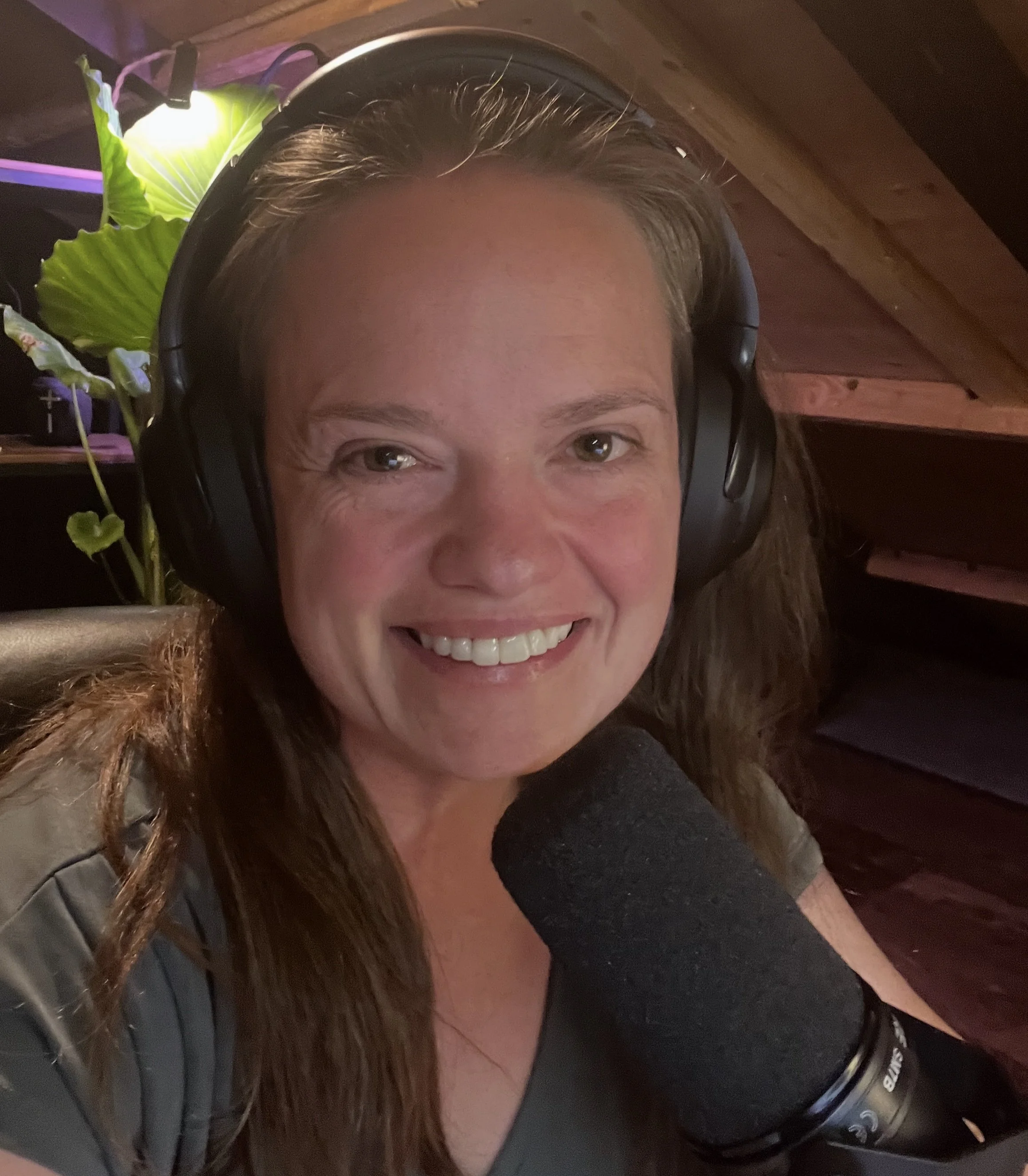 Laurel Lemohn smiling while recording the Spiritual Friction podcast with professional microphone and headphones in Longview, Washington