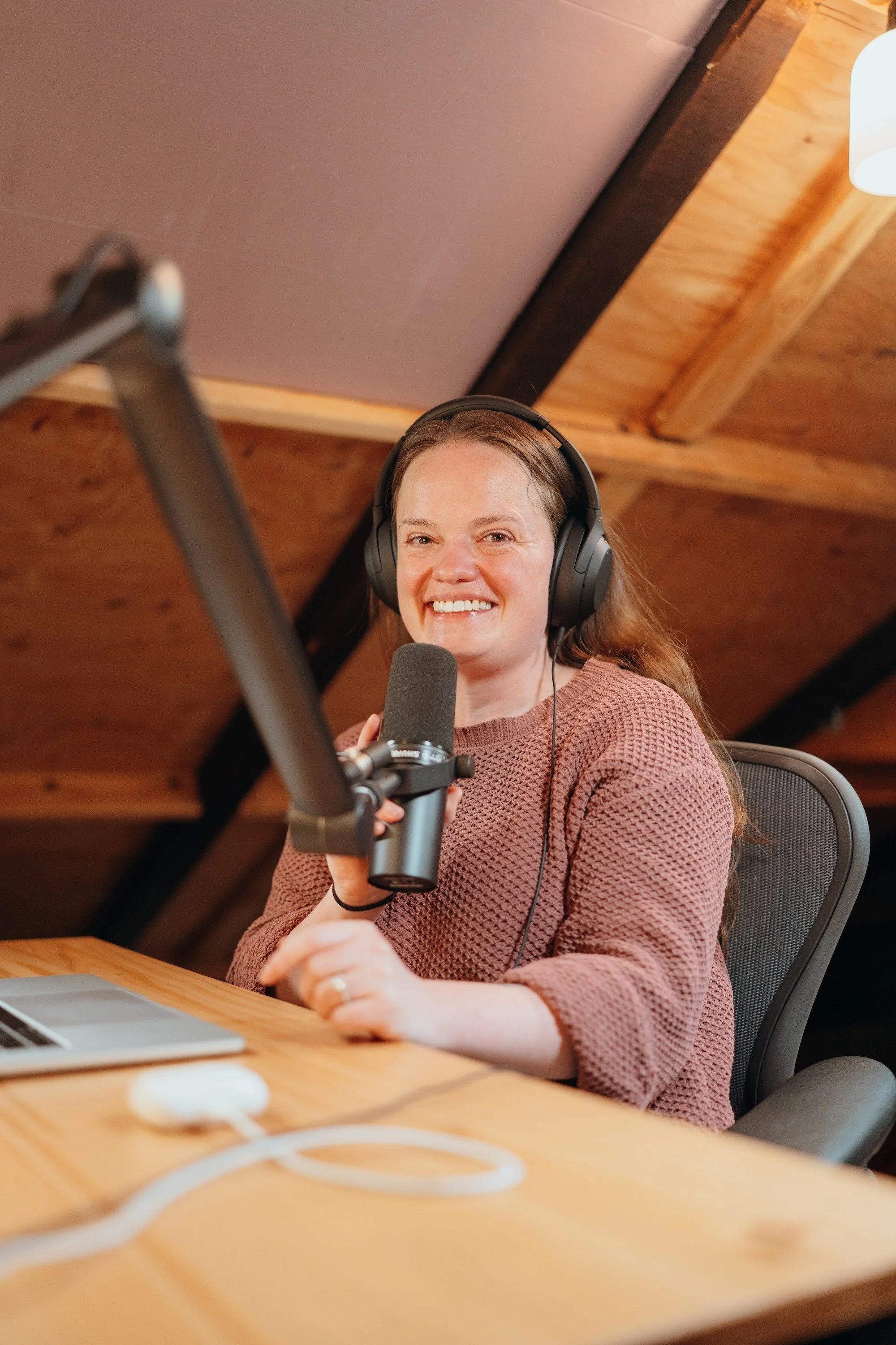 Laurel LeMohn recording the Spiritual Friction podcast at a table with headphones and a microphone