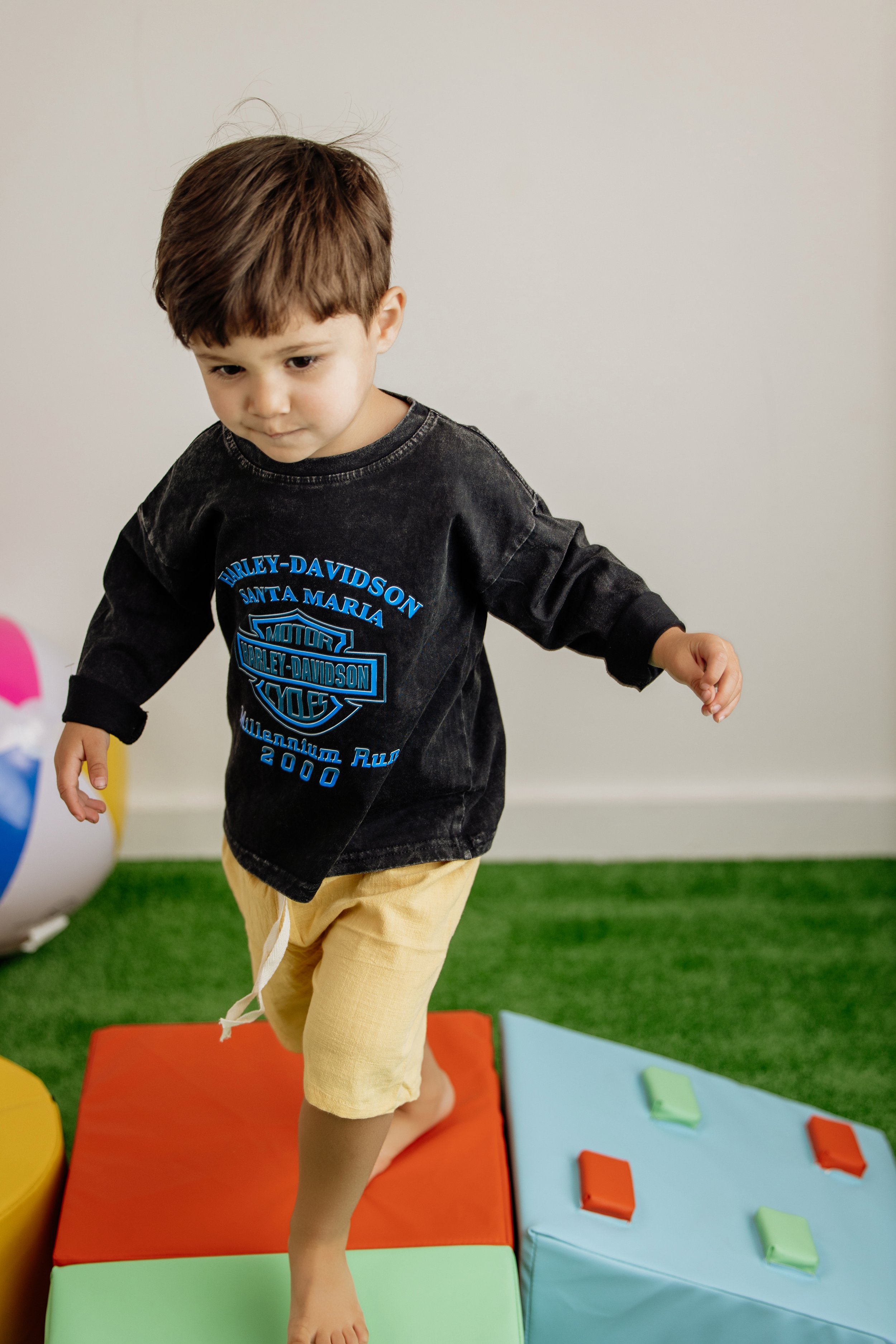 little boy is having fun on a plush play set in his soft organic yellow shorts from Lane Collins Co, Children boutique in North Georgia.