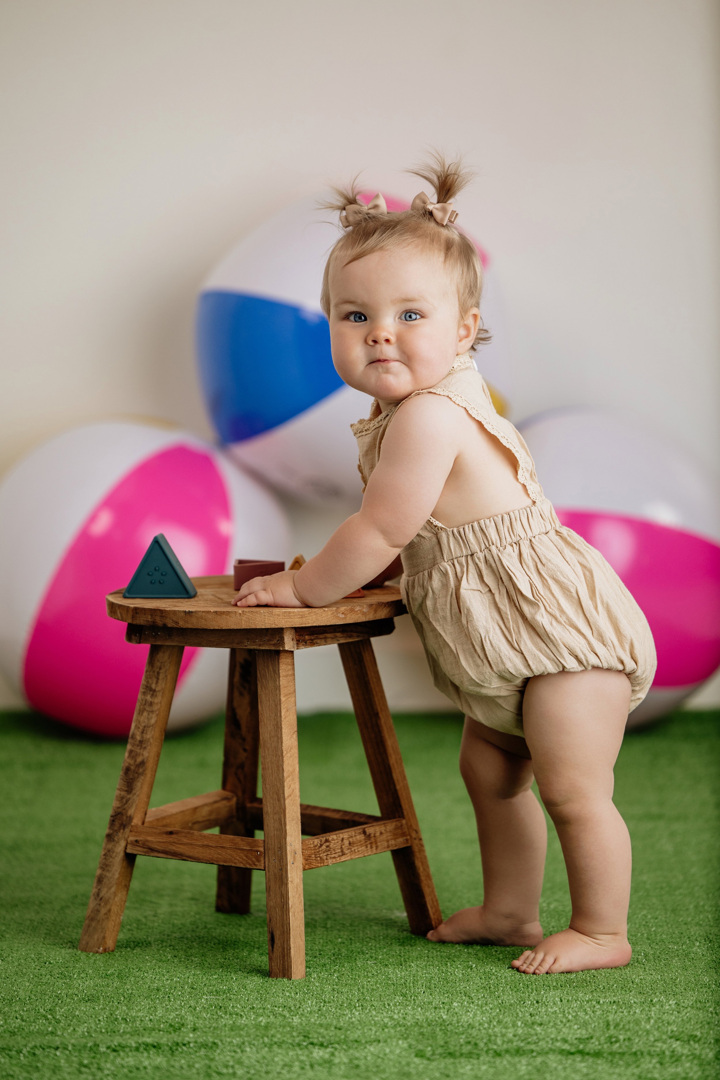 toddler girl is wearing an organic cottage romper and standing in grass next to a stool. Her outfit is from Lane Collins Co children's boutique in Dahlonega, GA