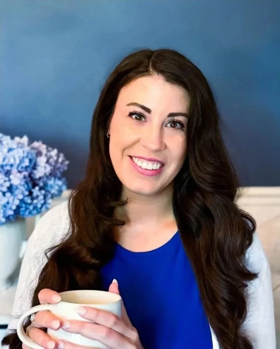 woman with long brown hair and bright smile holding coffee cup ready for virtual therapy about anxiety