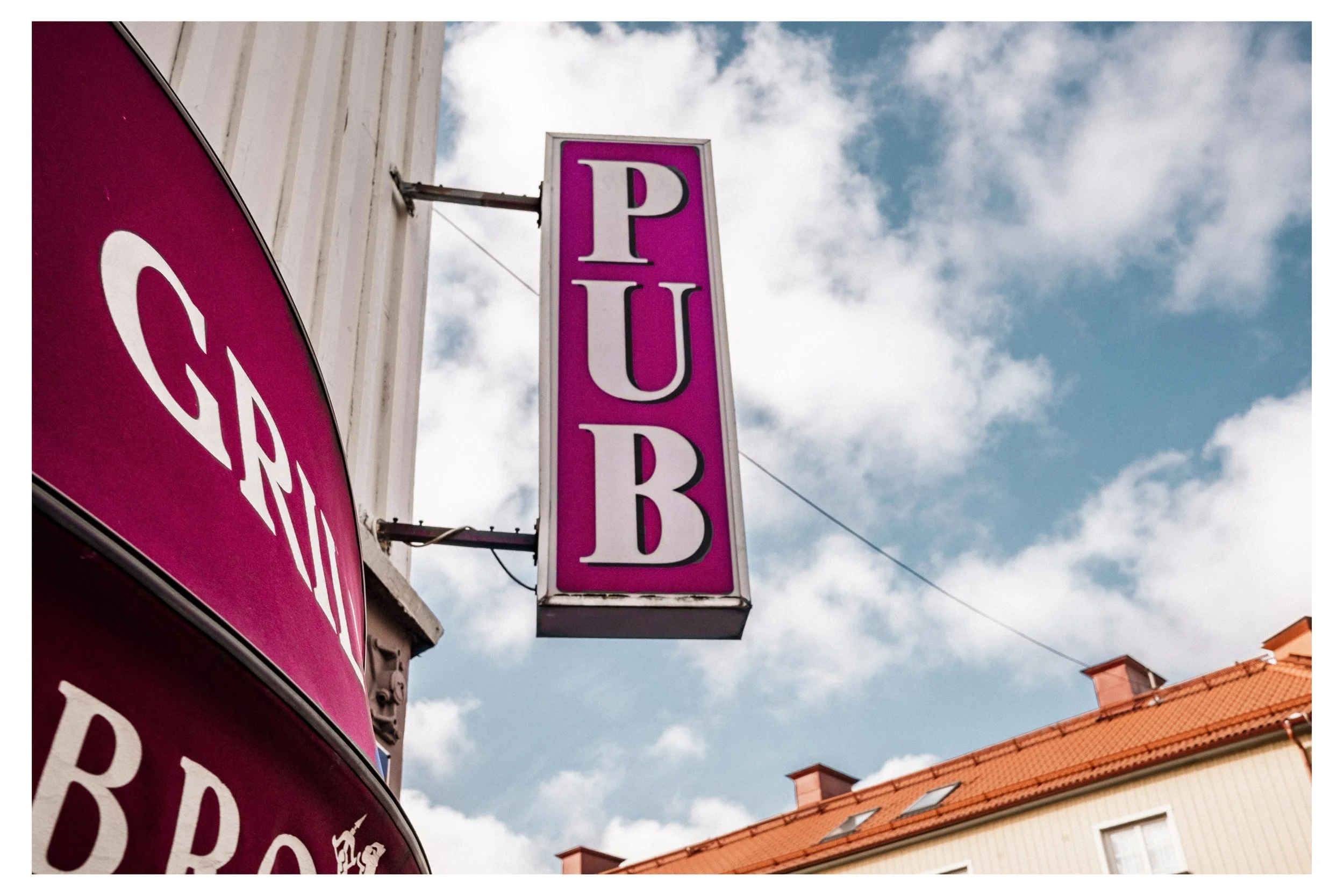 Skyltar för en butik eller restaurang, huvudsakligen rosa med vita bokstäver, som visar 'PUB'.