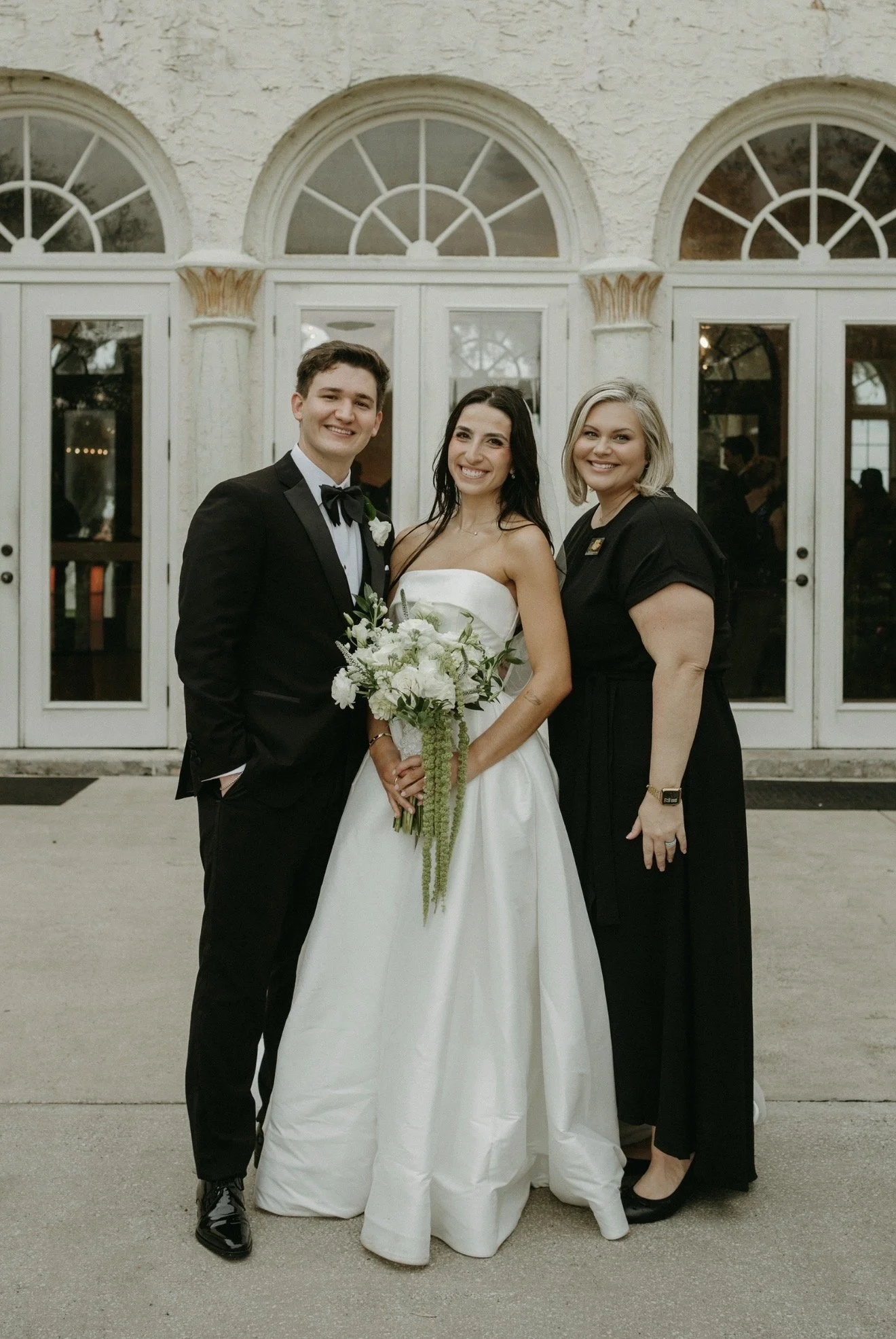 Bella and Juan smiling with their wedding planner from Something Blue Events outside Bella Cosa wedding venue in Lake Wales, Florida.