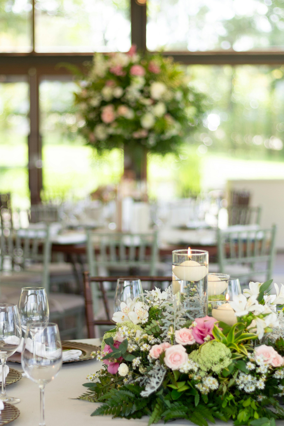 Elegant wedding reception featuring lush pink and white floral centerpieces, floating candles, and timeless table décor at a Central Florida wedding coordinated by Something Blue Events.