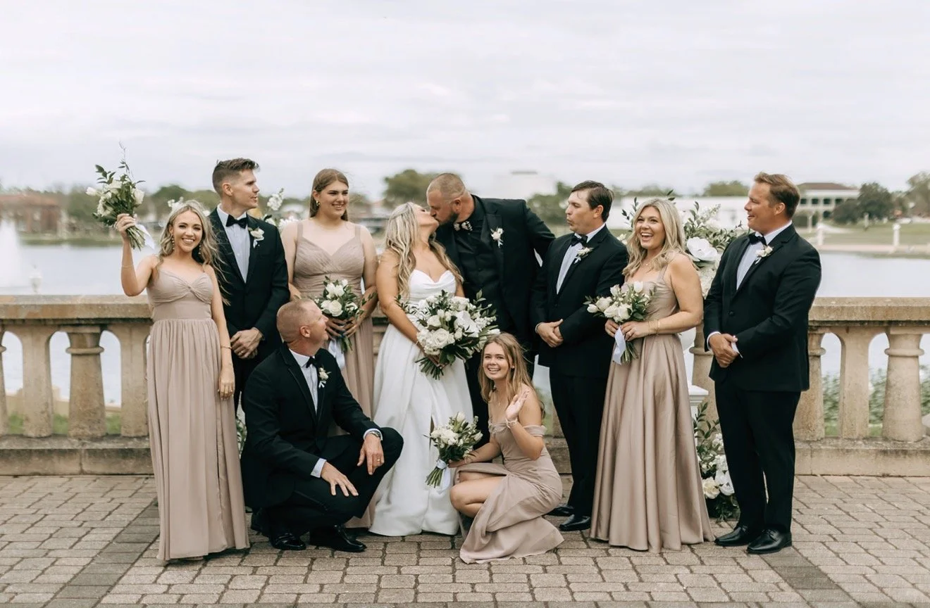 Bride and groom kissing with their wedding party cheering them on.