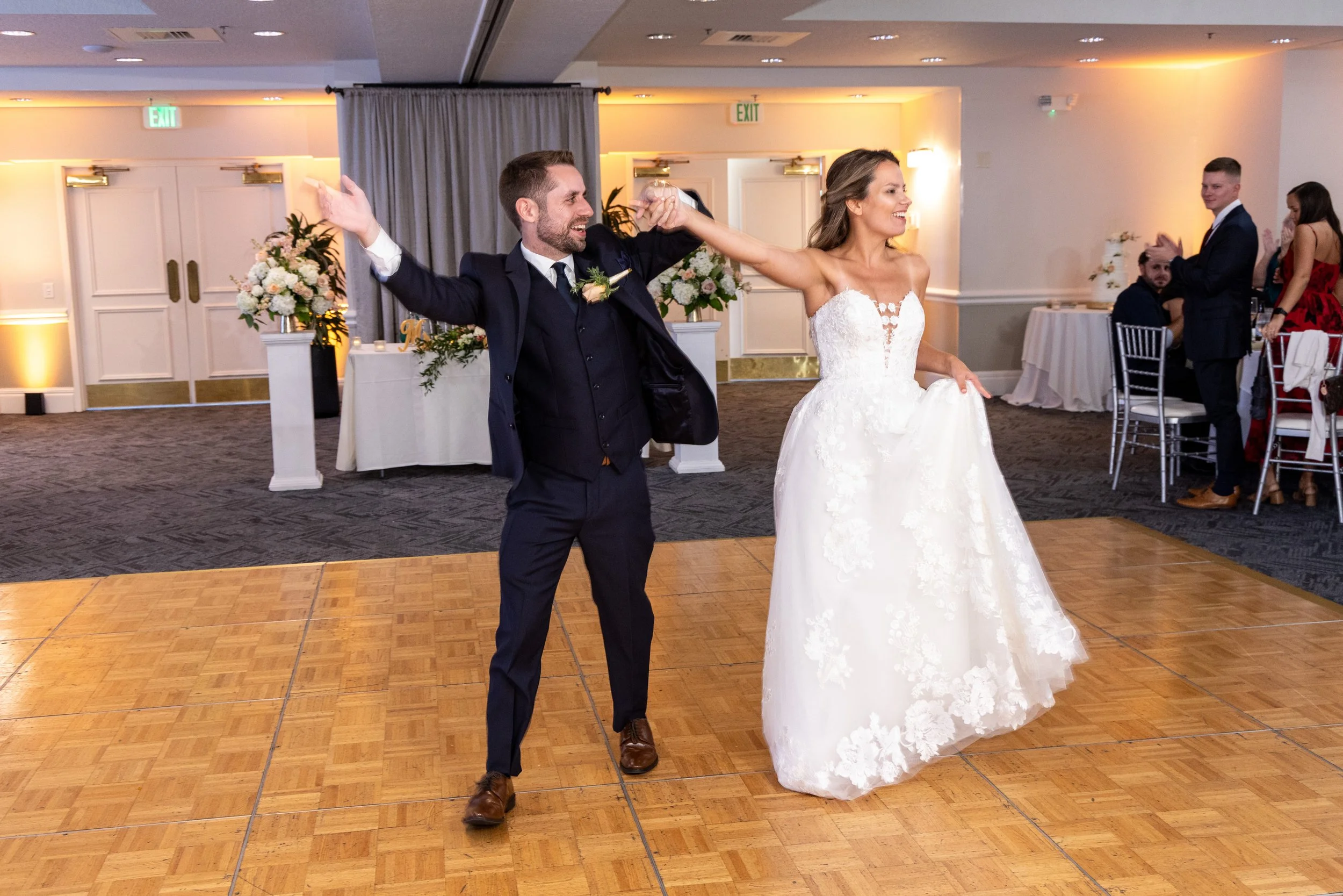 Newlyweds Kimberly and John smiling and raising their arms during their grand entrance onto the dance floor at Heathrow Country Club.
