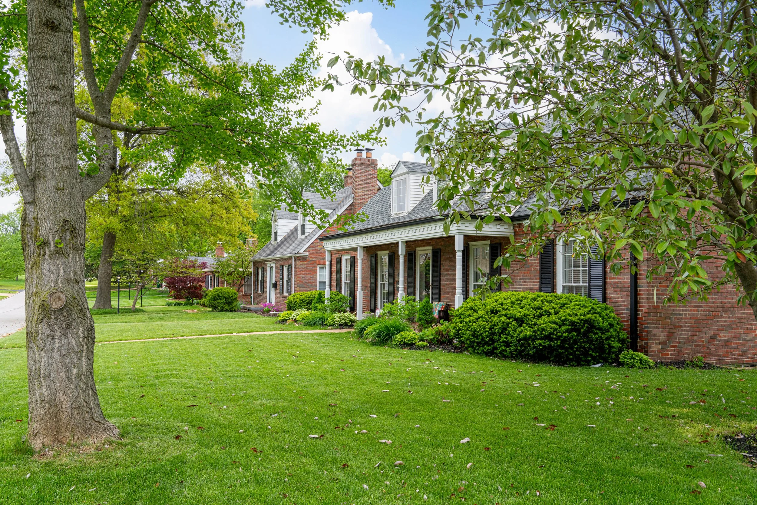 Beautiful brick home with a green lawn representing properties purchased as-is by Baborvit
