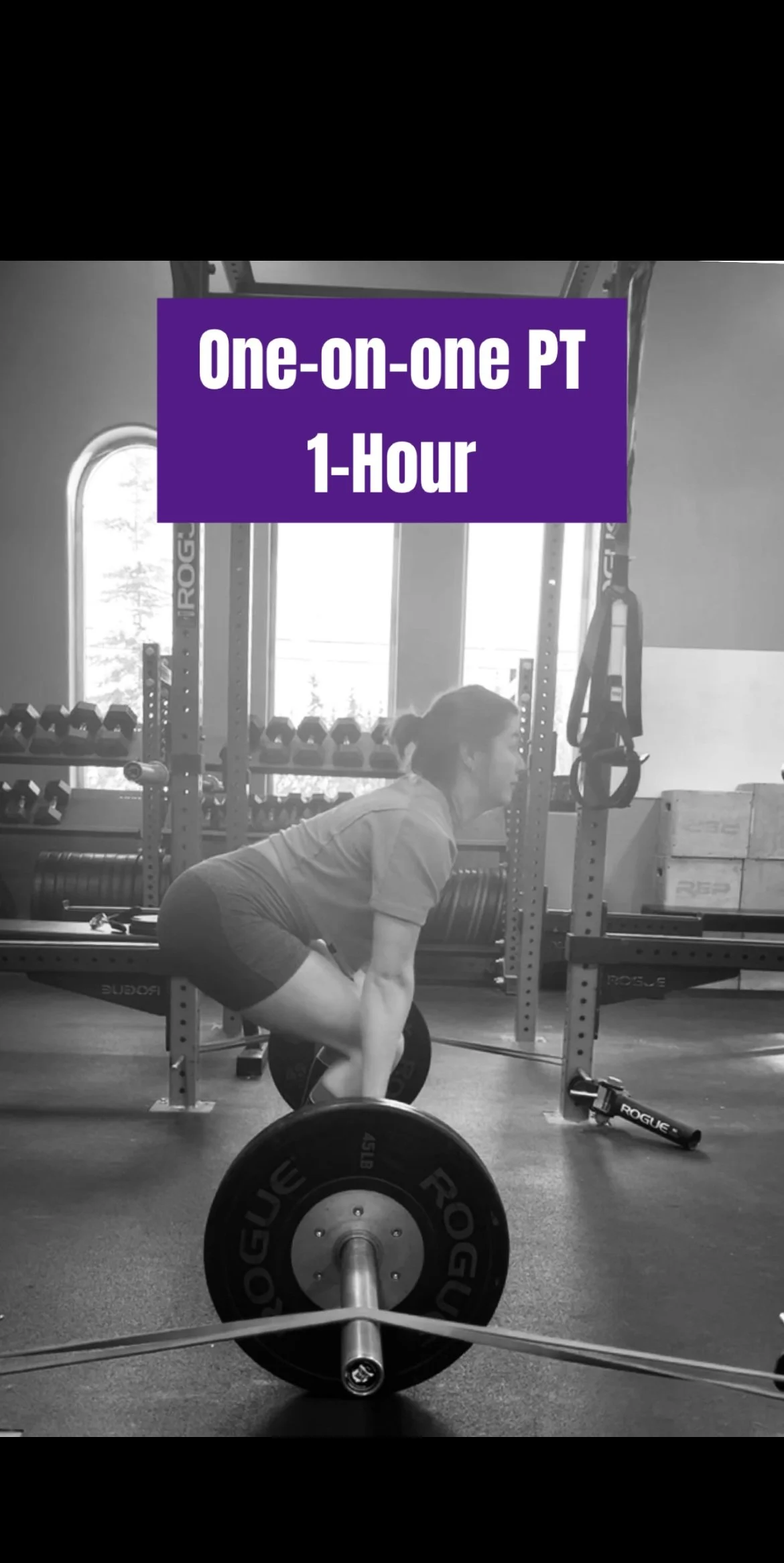 A woman with a ponytail performs a deadlift with a loaded barbell in a gym, with free weights and gym equipment visible around her, and a large window in the background.
