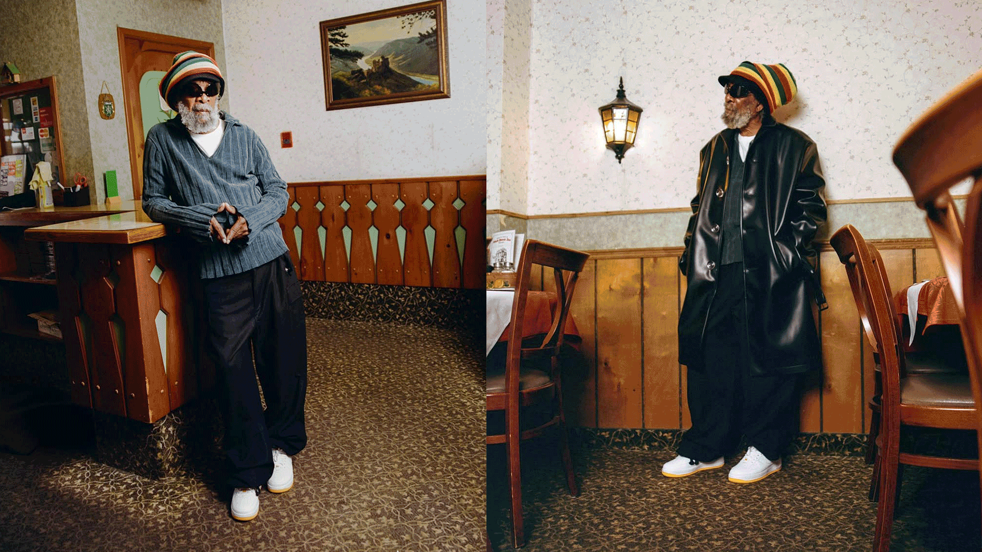 Two men standing in a restaurant, wearing colorful hats, sunglasses, and black outfits. The man on the left is wearing a striped beanie, a striped shirt, and white shoes, while the man on the right is wearing a rainbow-colored hat, a black leather trench coat, and white shoes. The restaurant has wood-paneled walls, framed landscape paintings, and patterned carpet.