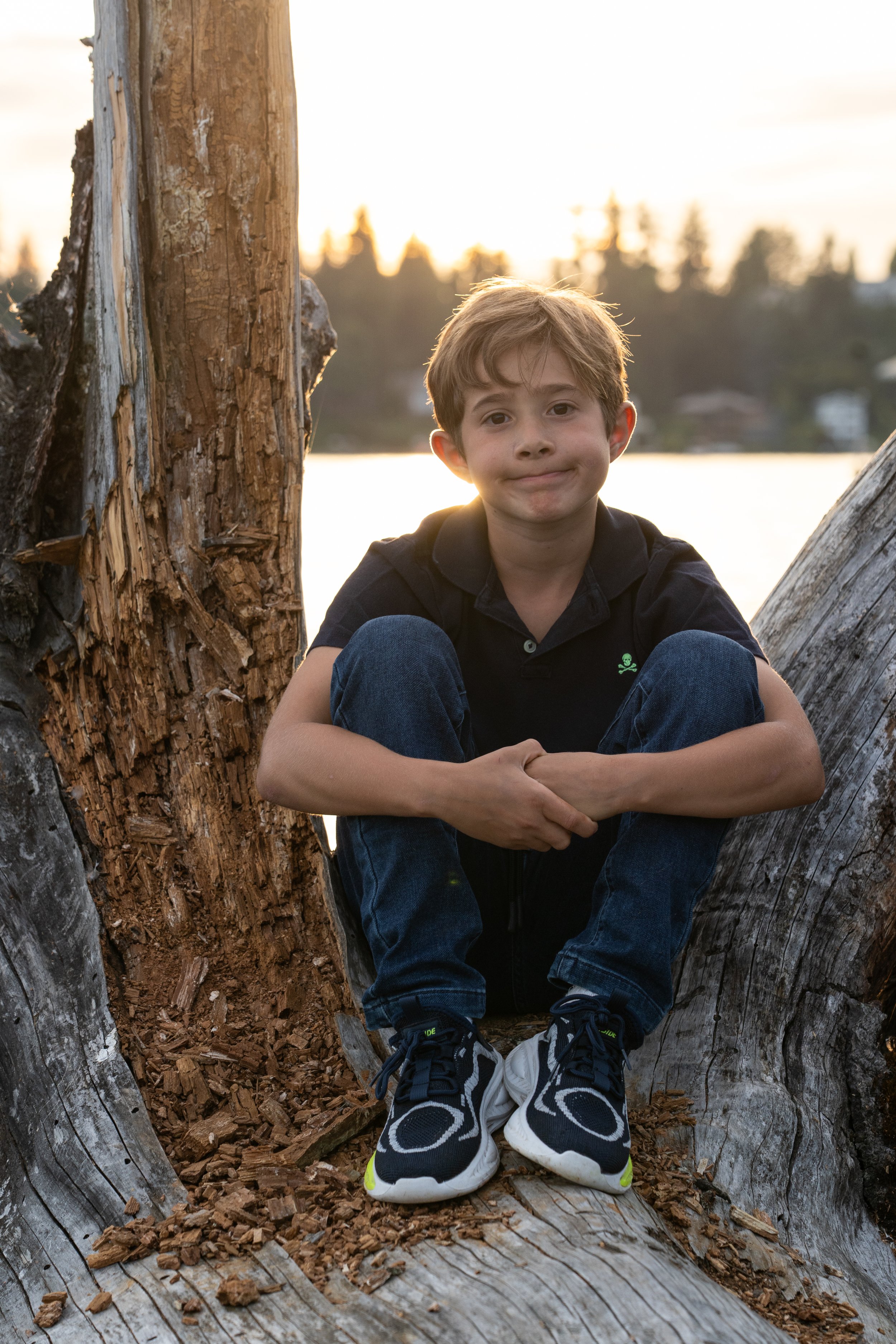 Young boy enjoying a golden hour portrait session on Mercer Island, framed by driftwood along the lakeshore. Natural, relaxed child photography by Rey Trey Photography.