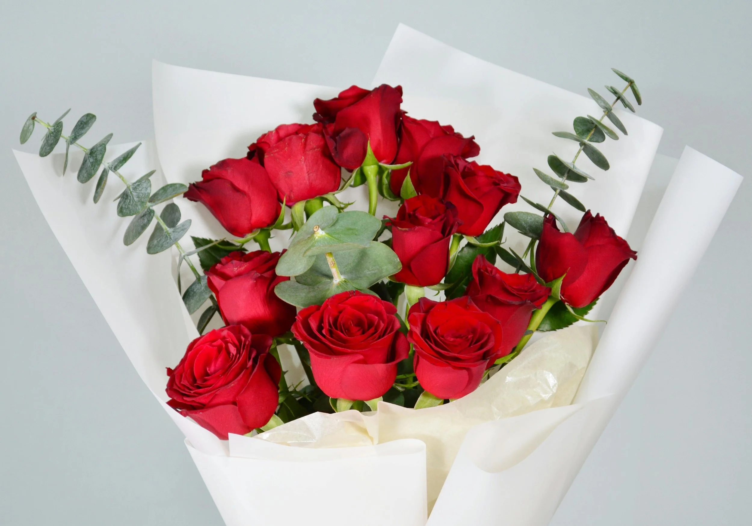 Bouquet of red roses and eucalyptus on white wrapping paper