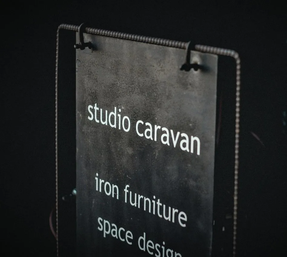 白字で「studio caravan」と書かれたアイアン製の看板