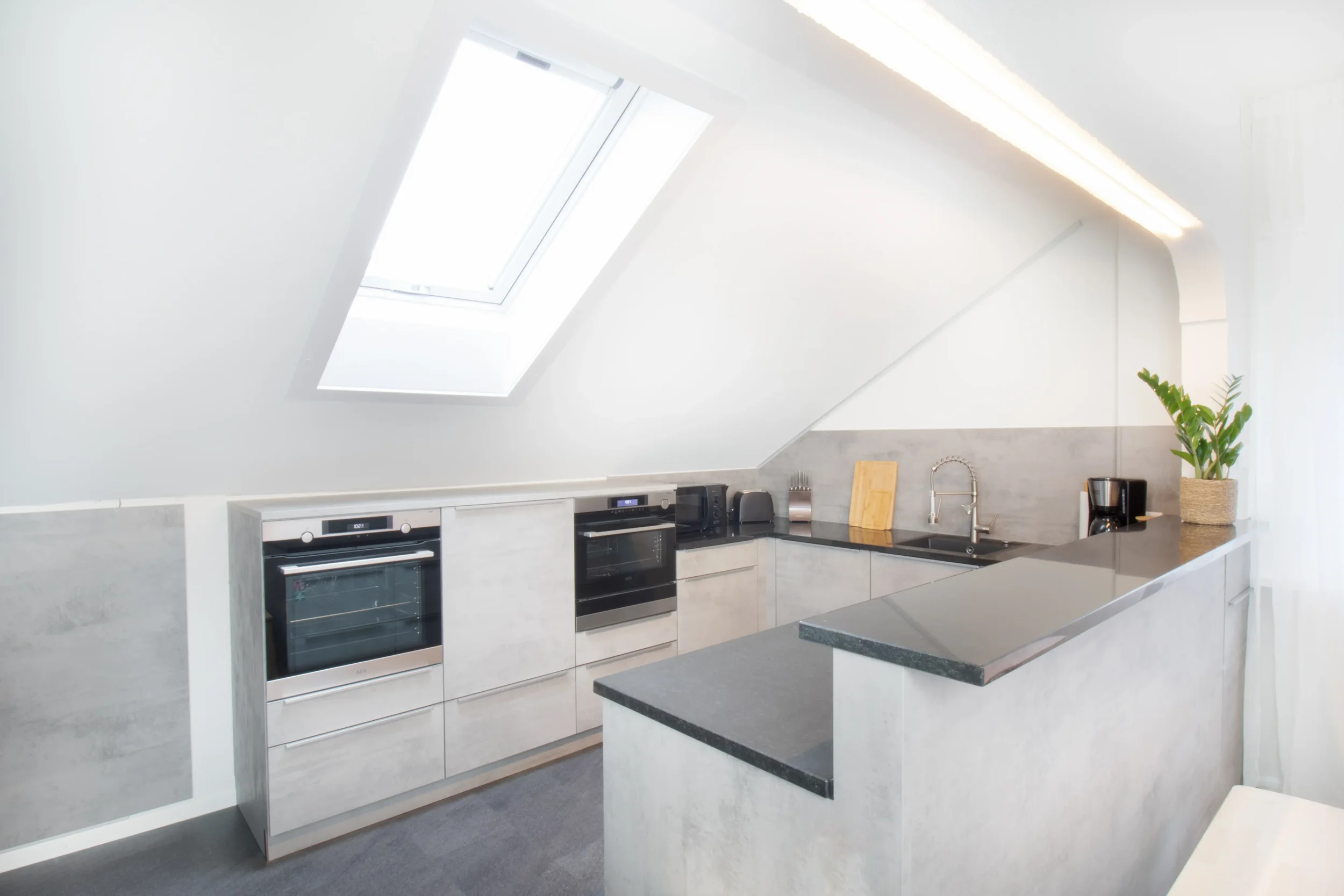 apartment-blau-kueche-kochinsel-dachfenster.webp