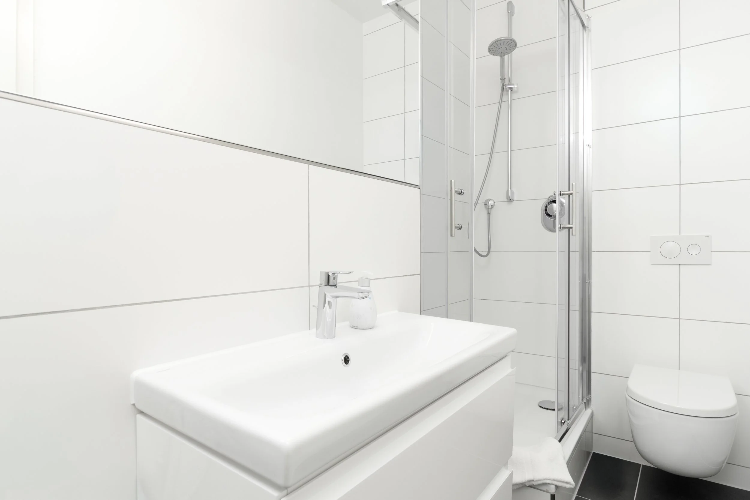 Modernes, helles Badezimmer mit großem Spiegel und gepflegtem Waschbereich – perfekt für den Start in den Tag.
