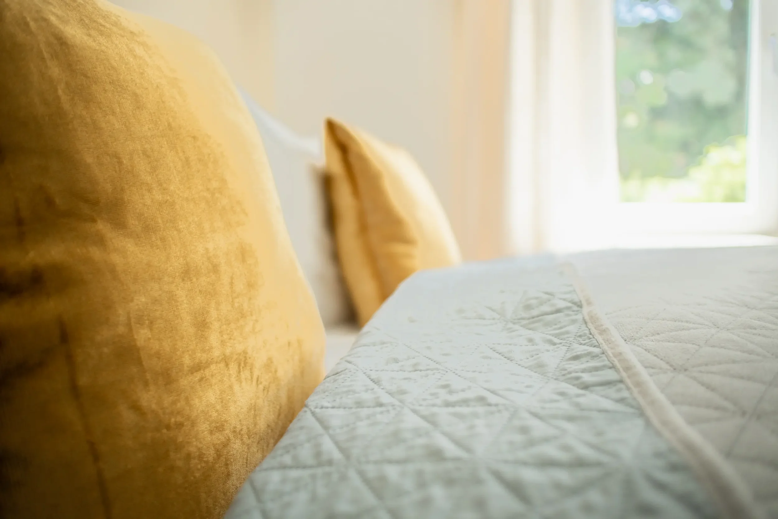 Detailaufnahme im Apartment Gold in Tiengen mit hellen Kissen und warmen gelben Akzenten