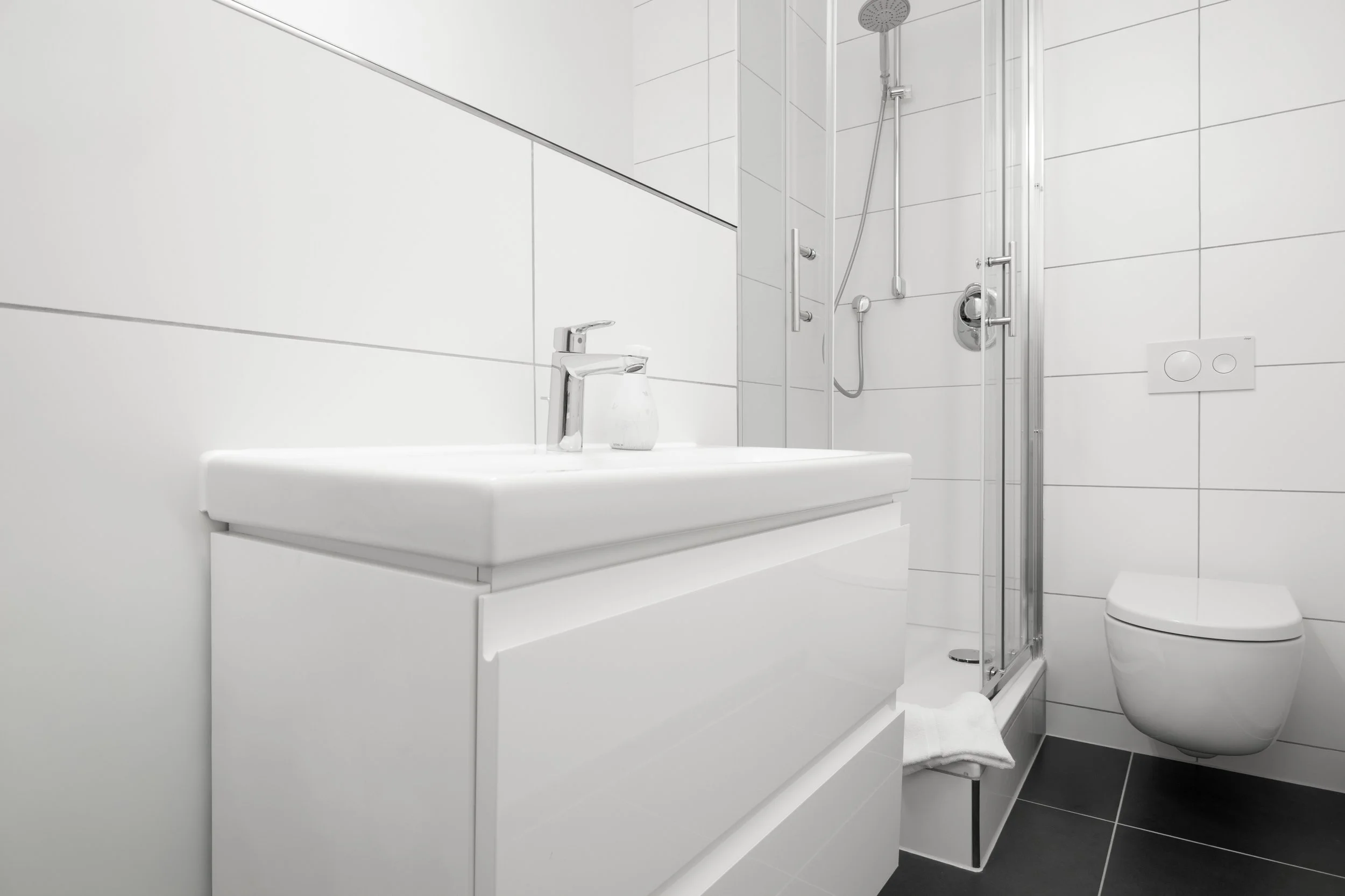 Heller Waschtisch mit klaren Linien und ausreichend Ablagefläche – alles sauber und modern eingerichtet.
