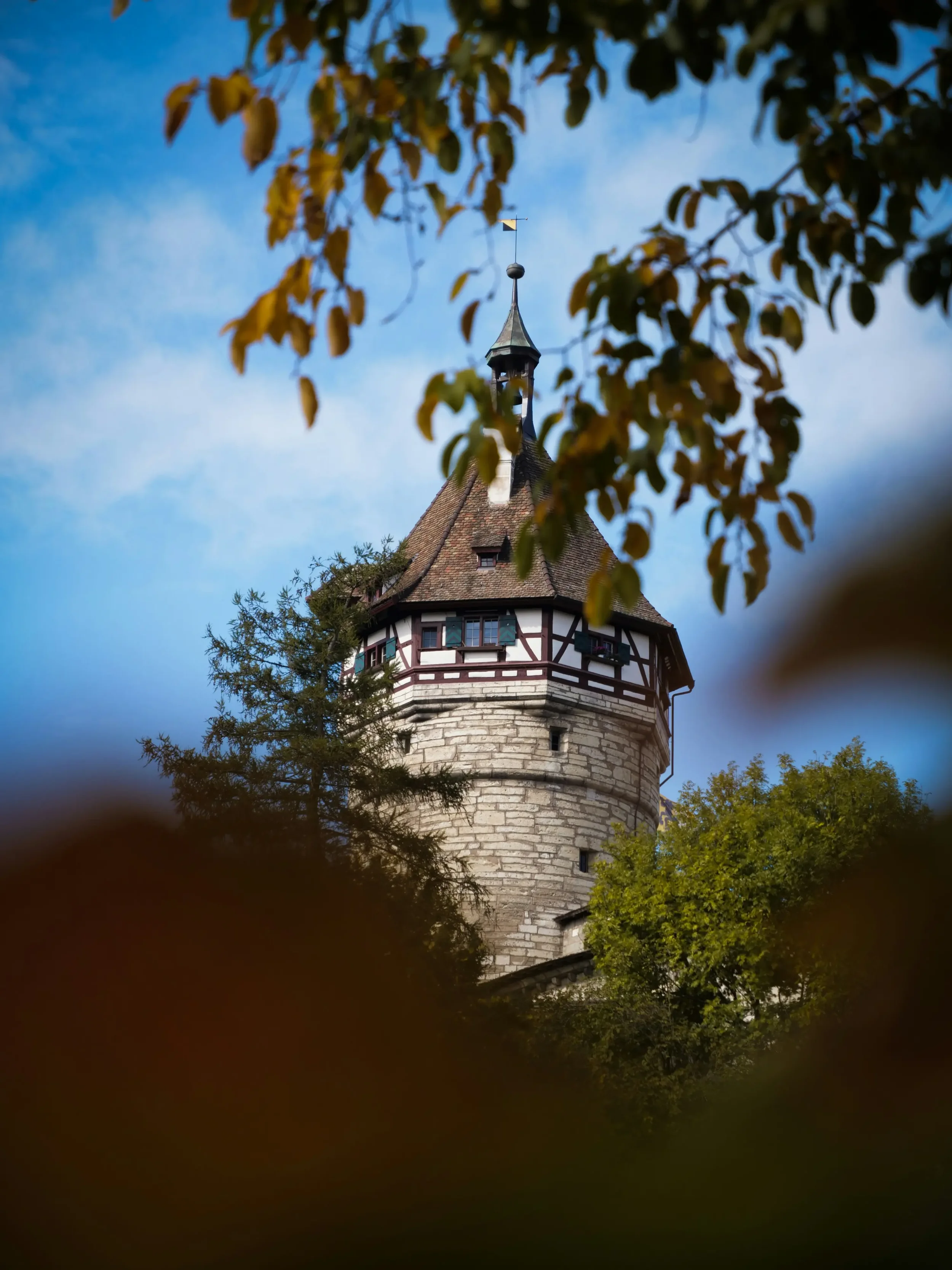 Munot en Schaffhausen - torre redonda con entramado de madera y vista sobre la ciudad, enmarcada por las hojas otoñales.