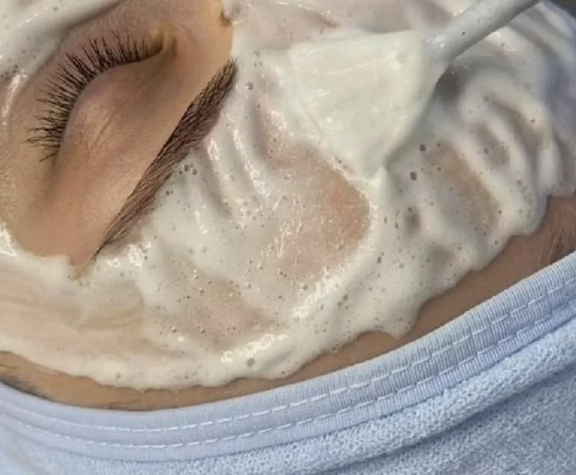 Une personne reçoit un soin du visage avec un masque ou un masque en mousse blanc.