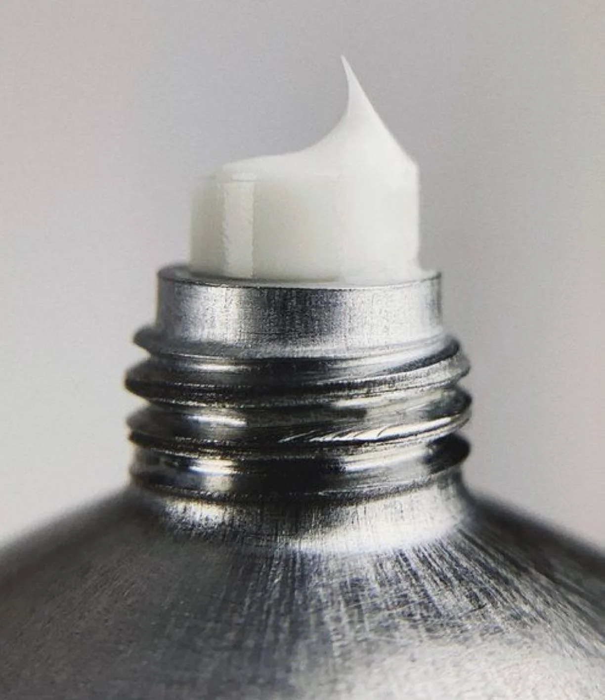 Tube de peinture métallique avec une pointe de peinture blanche en haut.