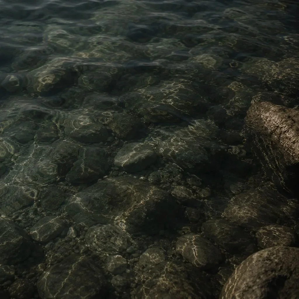Clear water with visible rocks and pebbles at the water's edge.