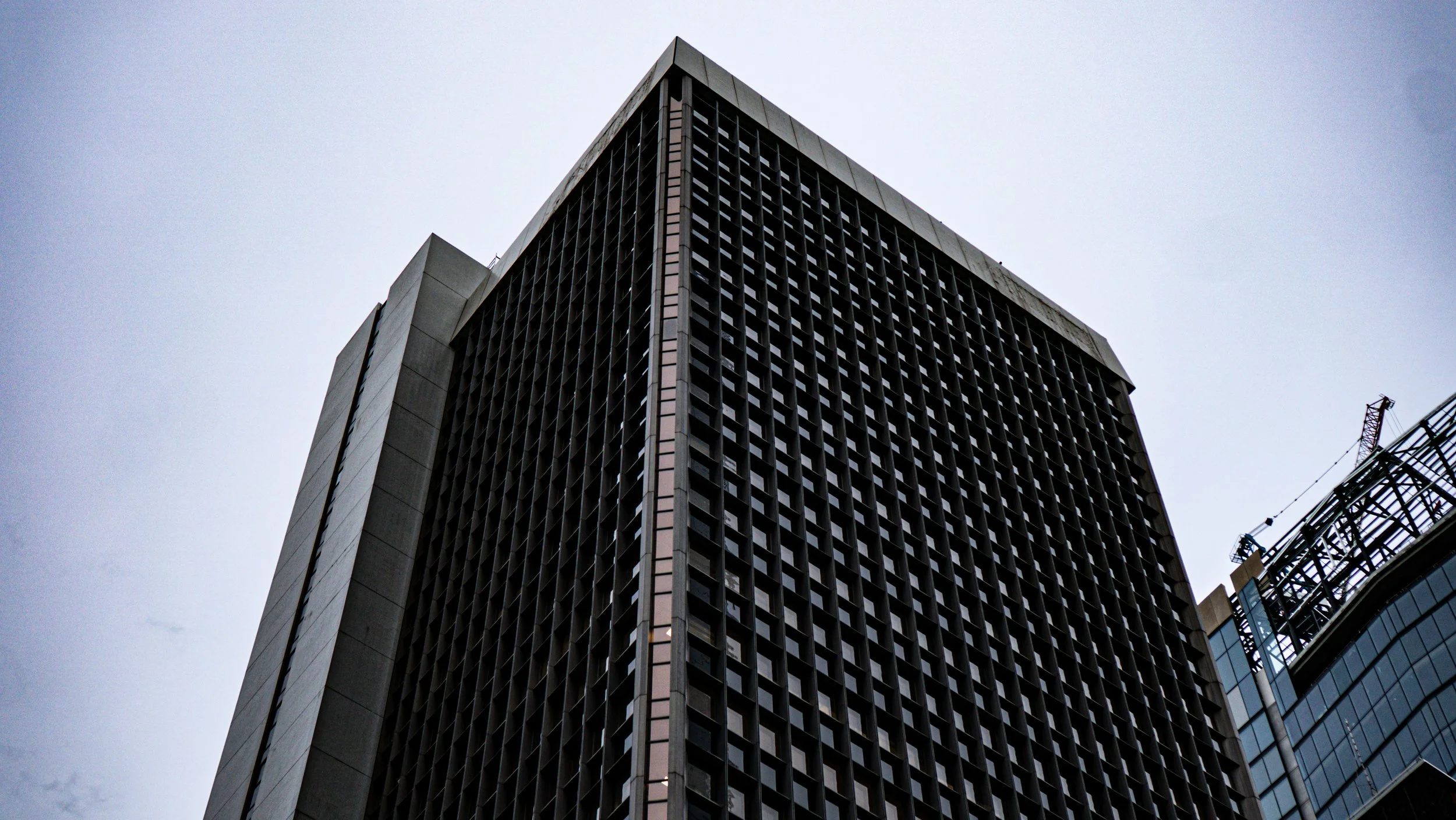 Tall modern city building with grid-like windows, shot from low angle on overcast day.