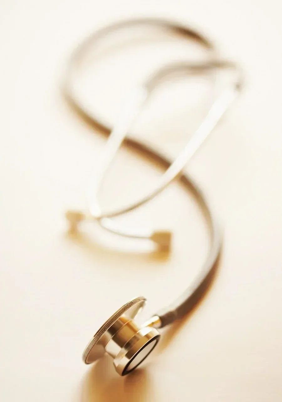 Close-up of a stethoscope with a metallic chest piece lying on a light-colored surface.