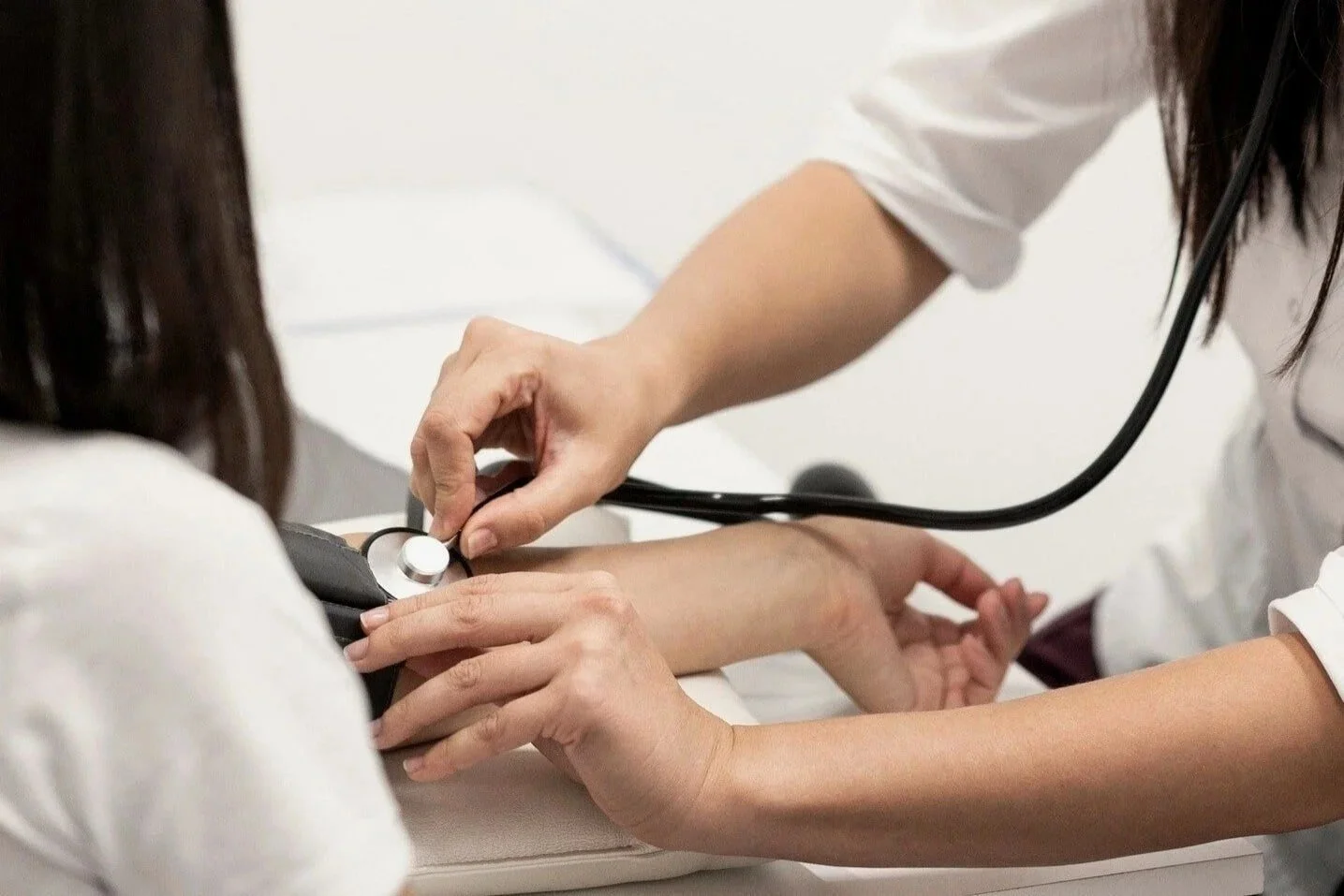 Medical professionals checking a patient's blood pressure with a sphygmomanometer.