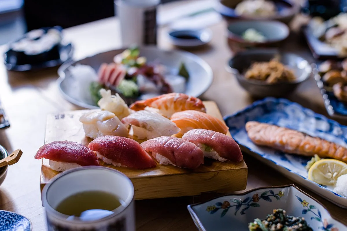 Sushi auf Holztablett, umgeben von weiteren japanischen Gerichten und Beilagen.