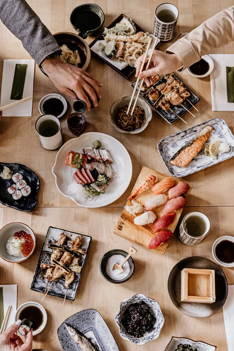 Japanisches Sushi und Sashimi auf einem Tisch mit Getränken und Beilagen