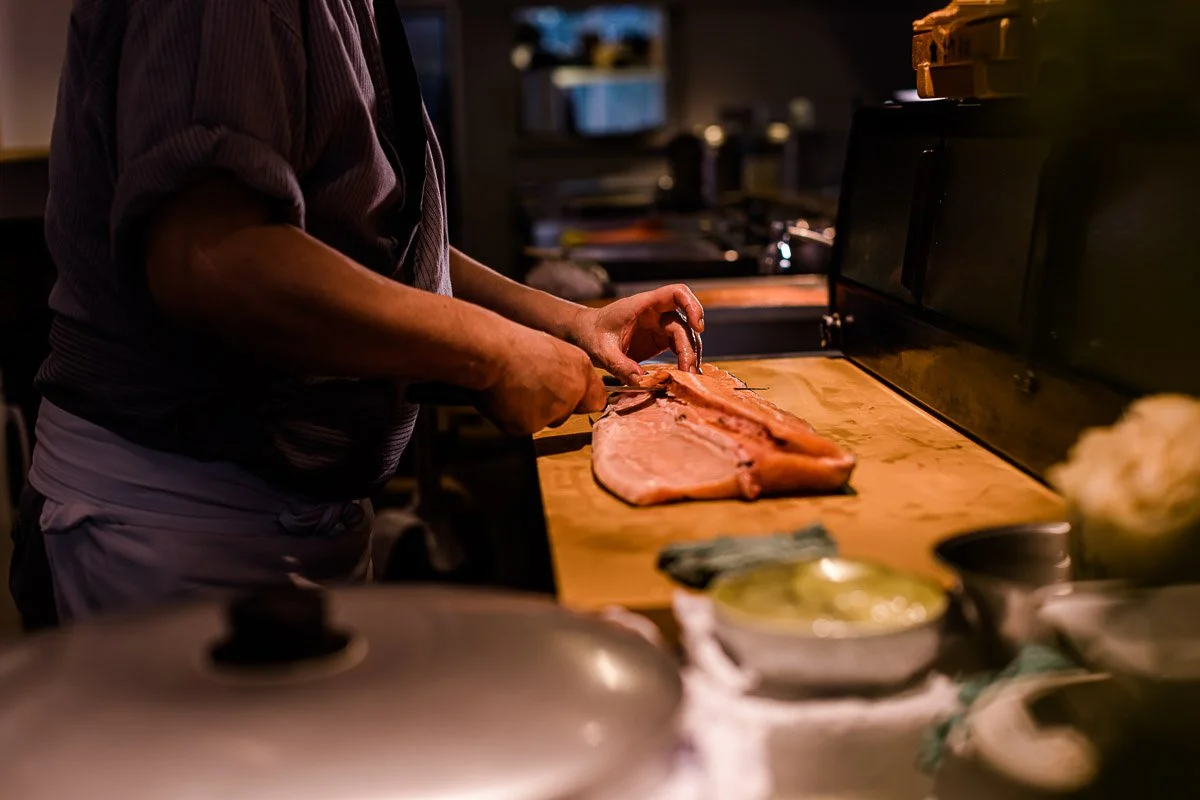 Jemand schneidet Fleisch in einer Küche.