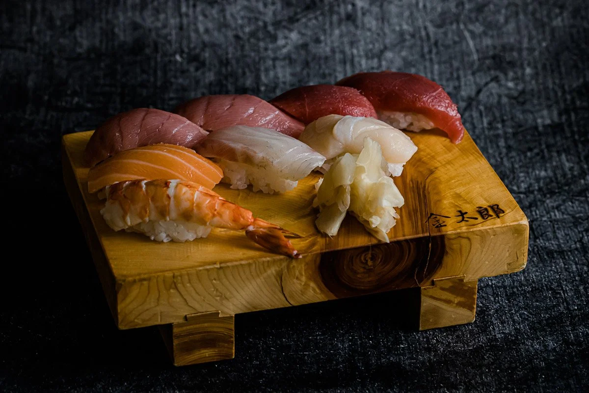 Sushi-Platte mit verschiedenen Fischsorten und Garnelen auf einem Holztablett