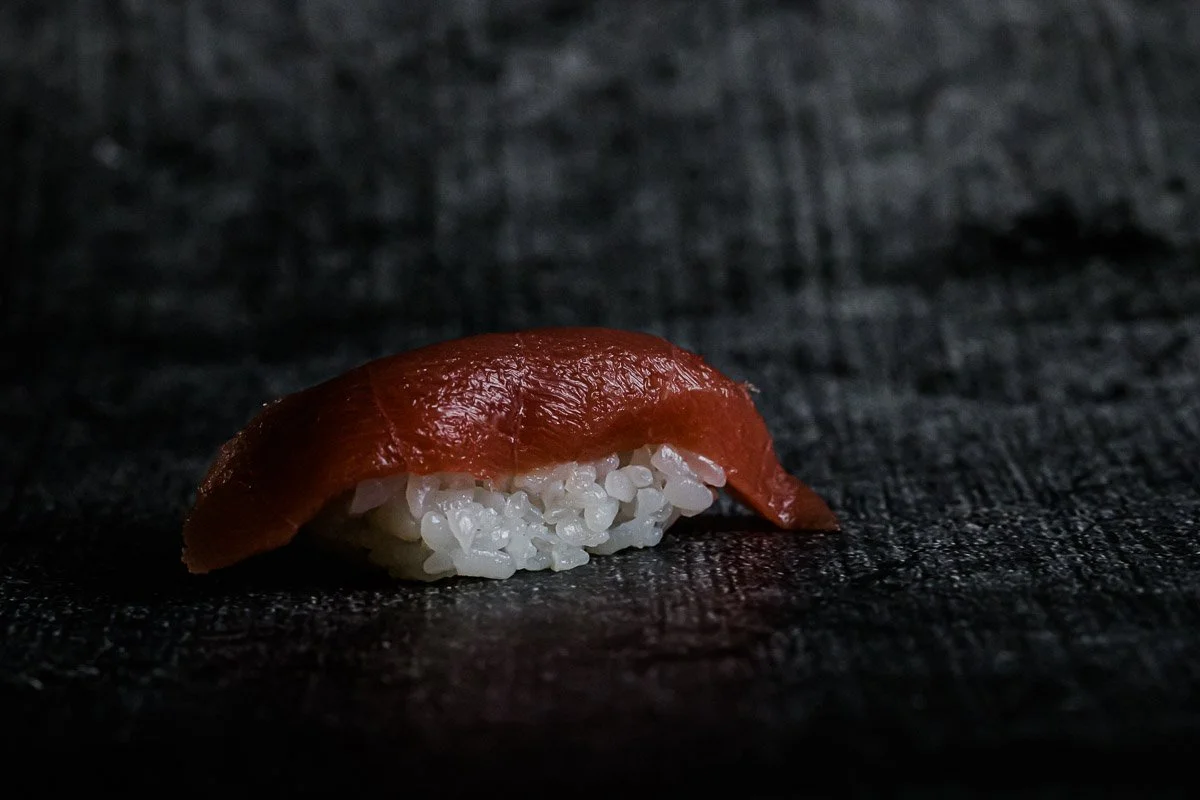 Nahaufnahme von einem Lachs-Nigiri Sushi auf einem schwarzen Hintergrund.