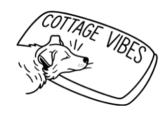 A dog resting its head on a bed that says 'Cottage Vibes'