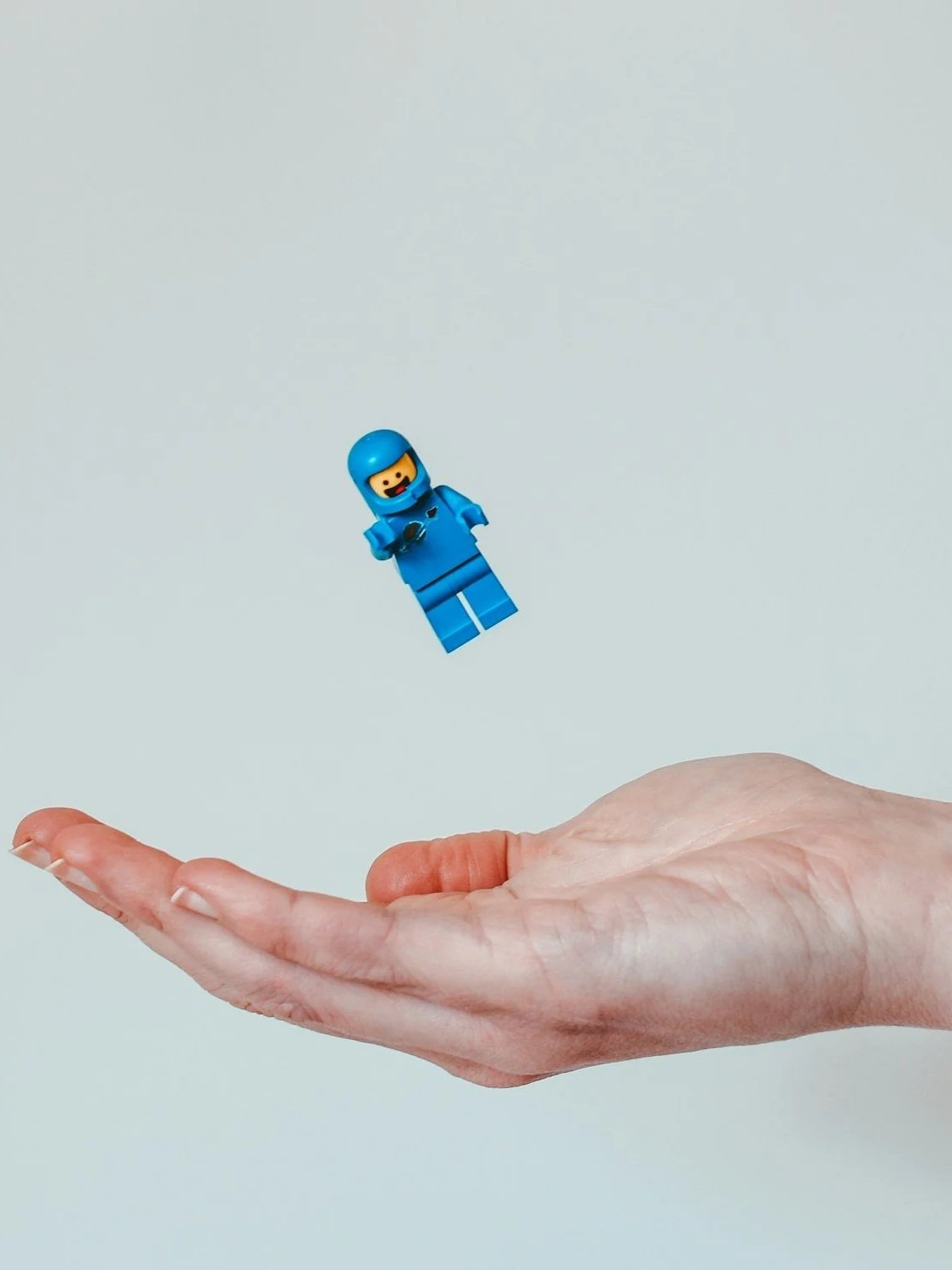 Serious Play Iceland, LEGO námskeið, A hand holding out a finger with a LEGO astronaut minifigure floating above it against a white background.
