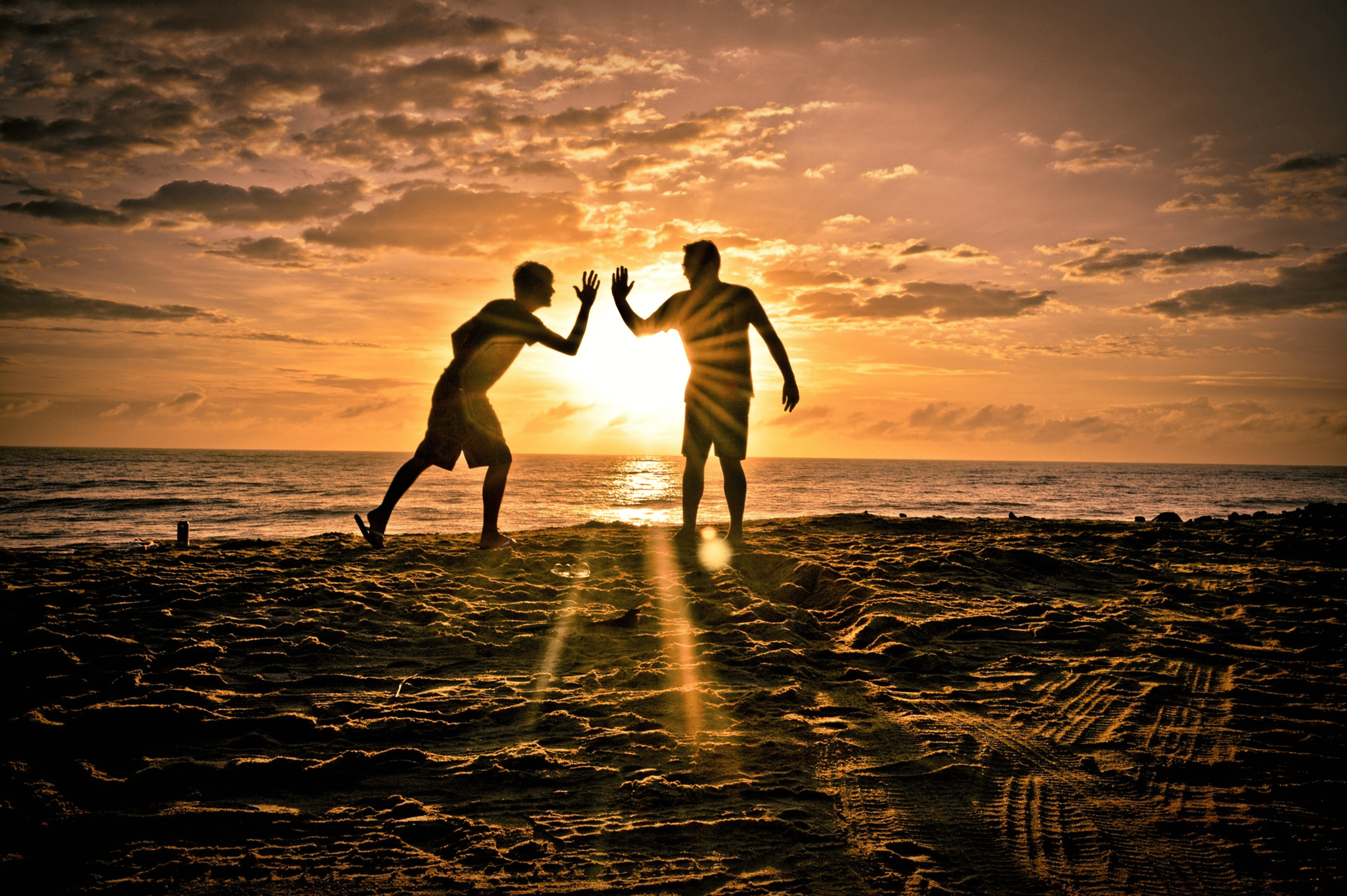 Deux silhouettes jouant sur une plage au coucher du soleil