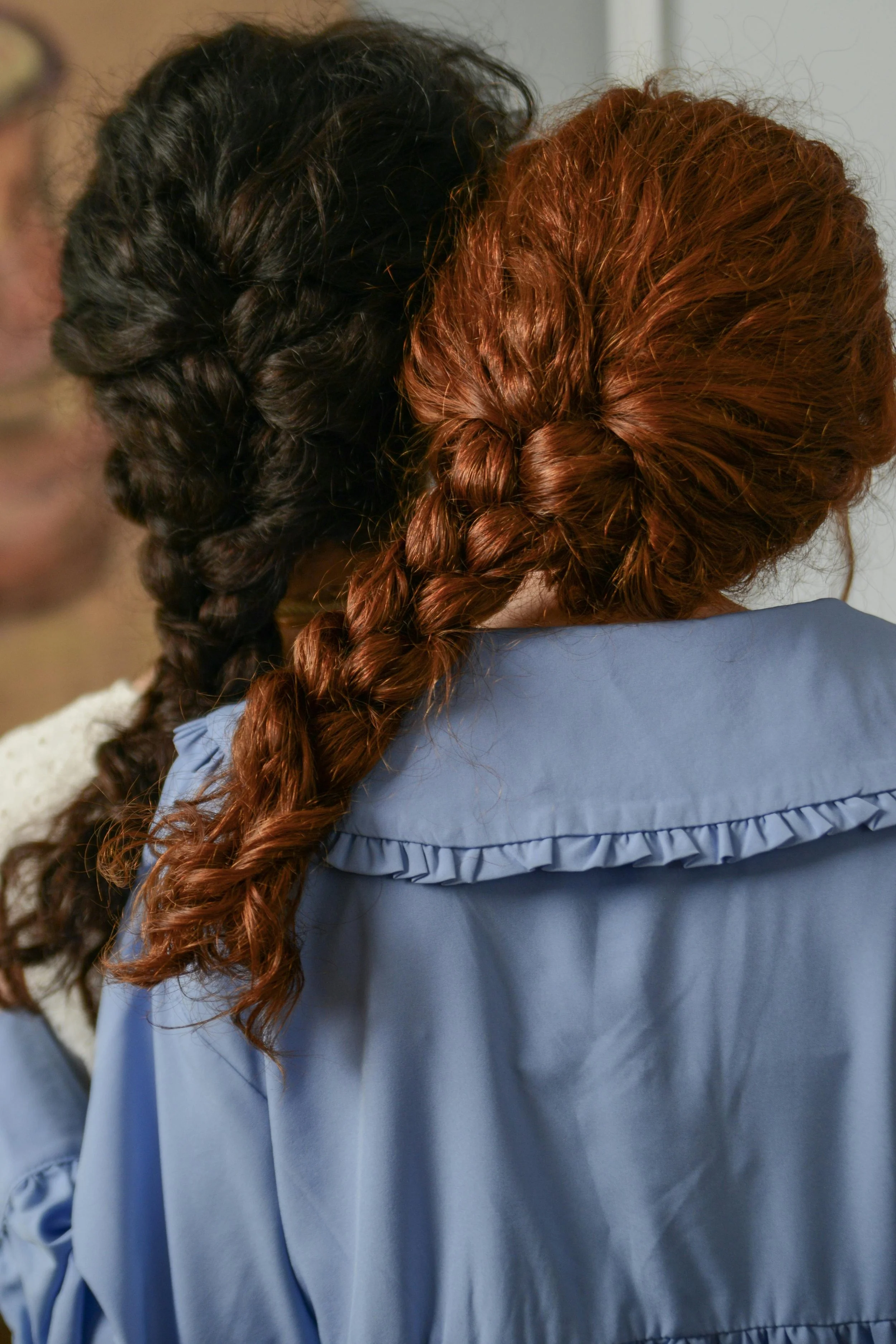 Close-up view of two women with braided hair, one with black hair and the other with red hair, wearing blue uniforms.