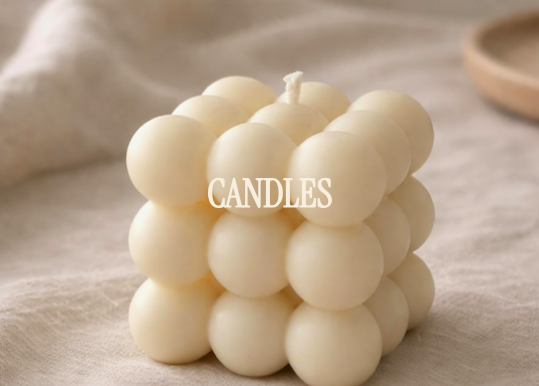A cubic cluster of white spherical candles with the word 'CANDLES' overlaid in the center, set on a neutral fabric background.