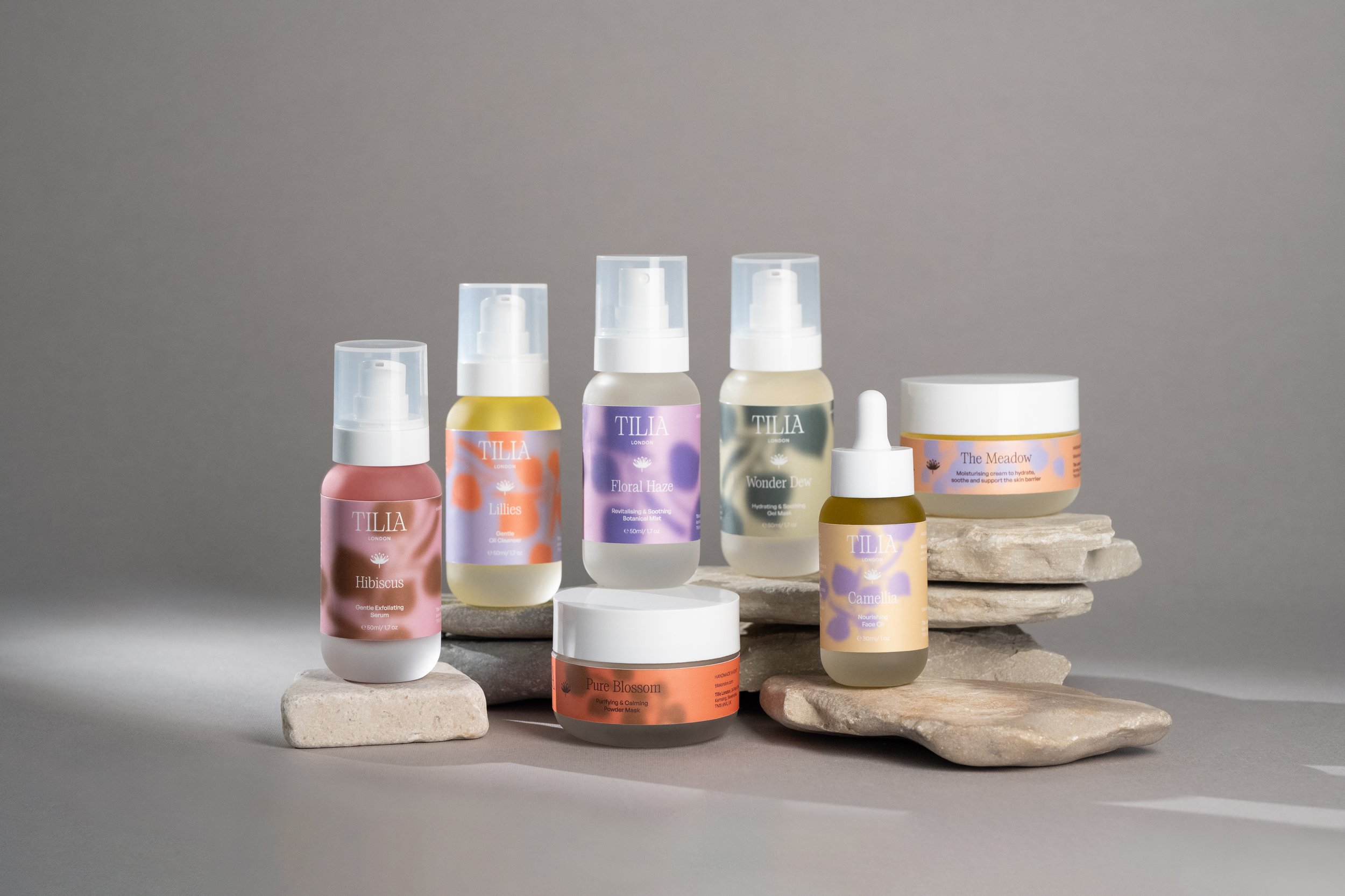 Assorted Tilia London skincare and cosmetic products displayed on stacked stones and a flat surface against a neutral background.